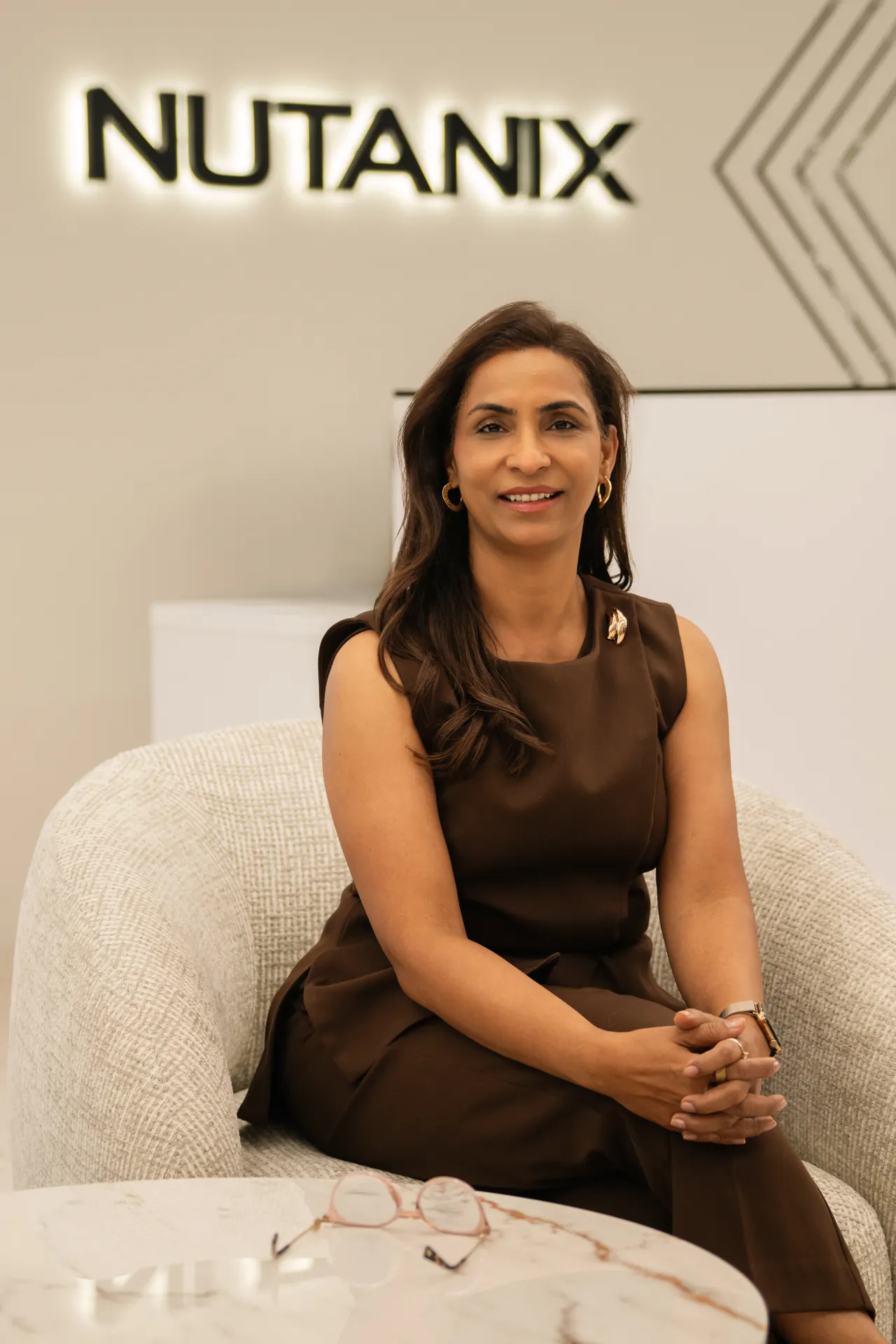 Seated portrait in a brown dress with the Nutanix logo behind. On-site corporate headshot at the Nutanix office in Dubai.