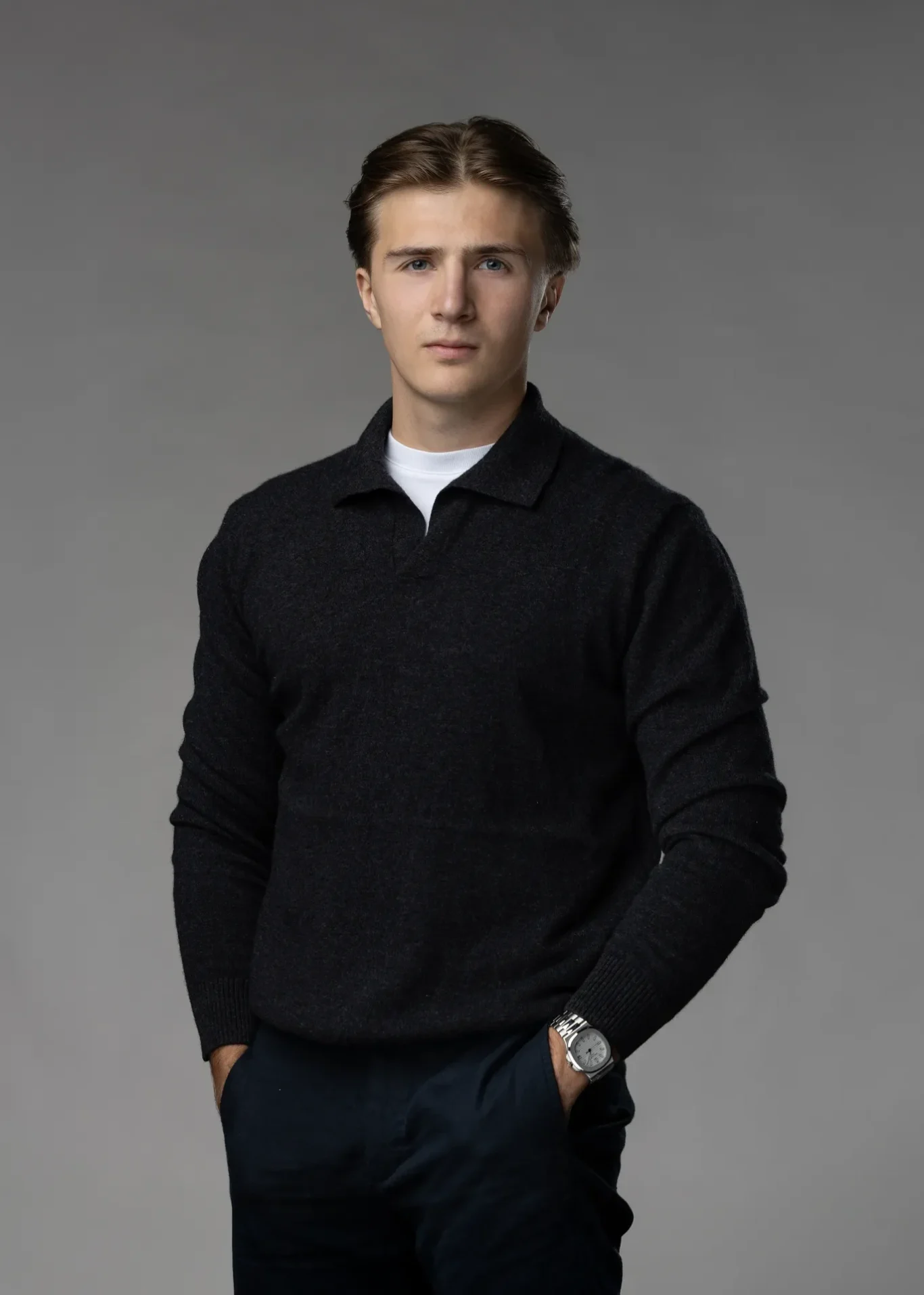 Relaxed standing portrait with one hand in a pocket, black knit sweater, dark grey backdrop. Editorial business portrait by MRPS in Dubai for a financial magazine feature.