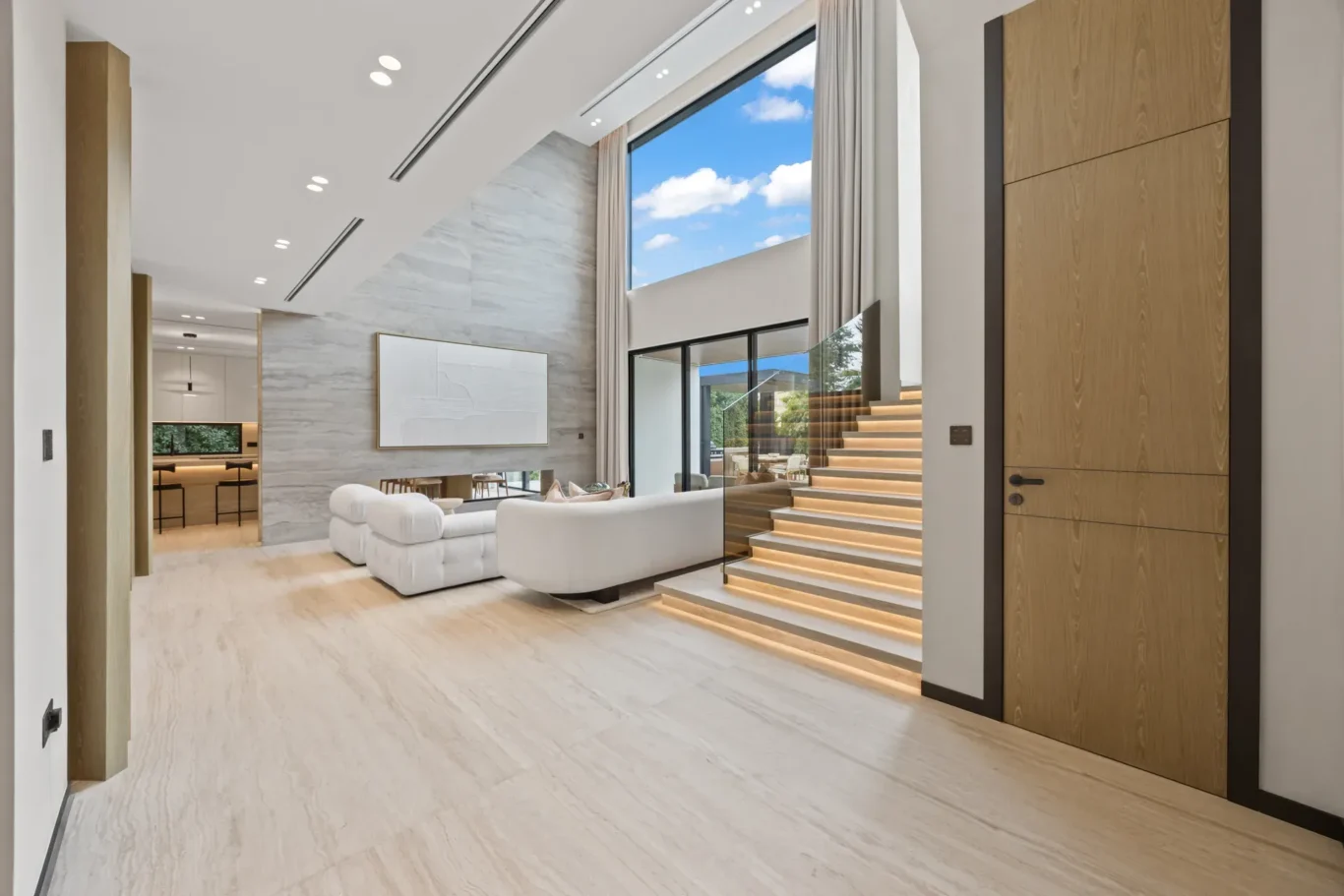 Double-height living room seen from the hallway beside the staircase, luxury villa in Jumeirah Islands, Dubai.