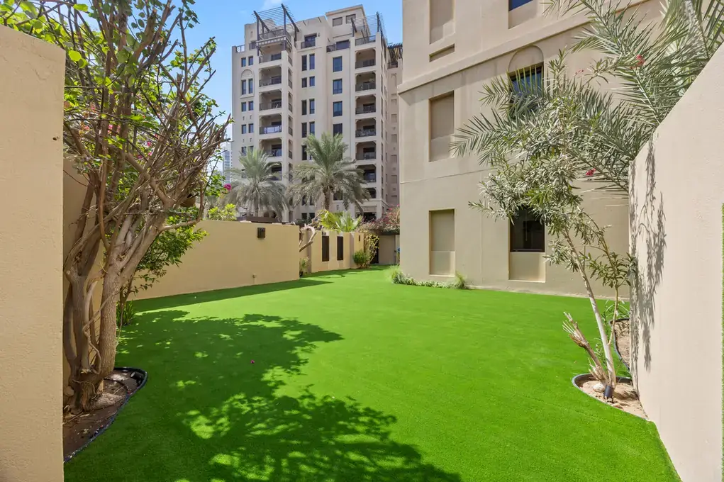 Lawn garden with palm trees and Old Town facades in an unfurnished two-bedroom garden apartment in Old Town, Downtown Dubai, photographed for ELITE Property Brokerage.