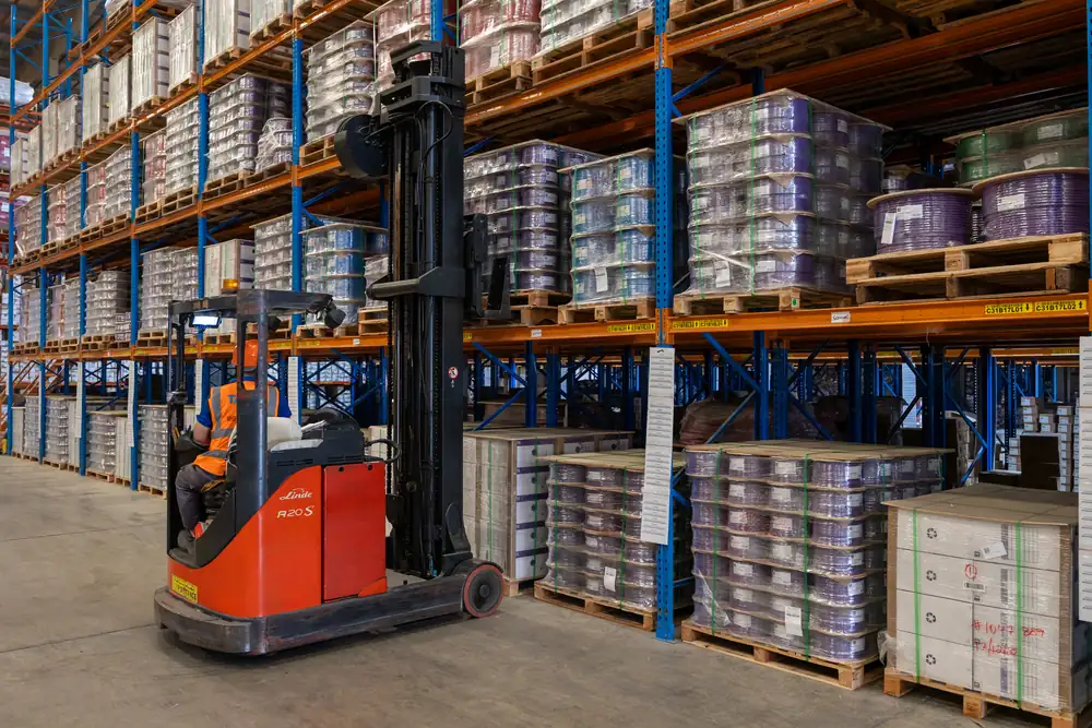 Reach truck operator lifting a pallet of cable reels into high racking during the B3 International warehouse shoot in Dubai.