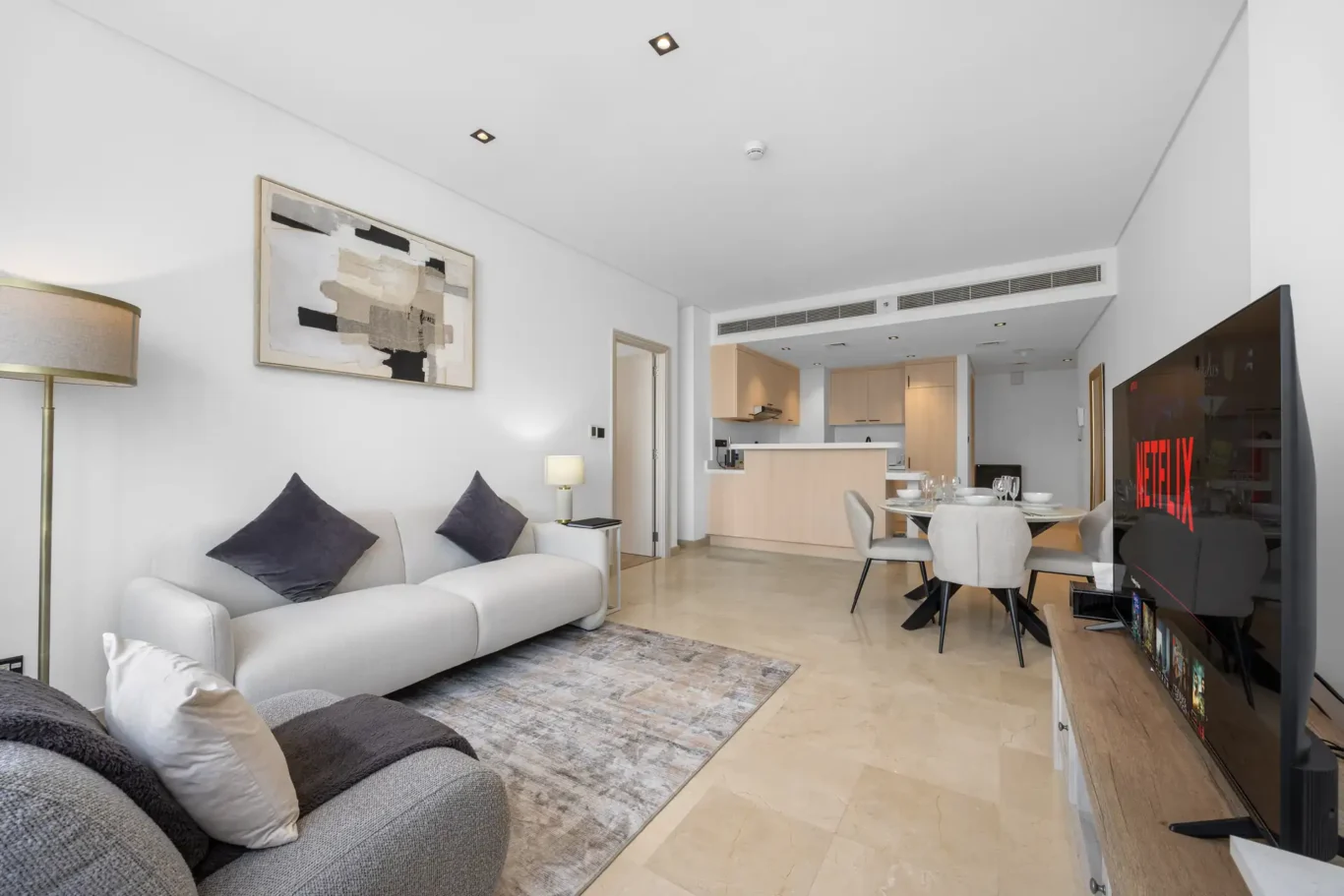 Living and dining area with smart TV in a Your Stay Apartments one-bedroom at Sky Gardens, DIFC, Dubai.