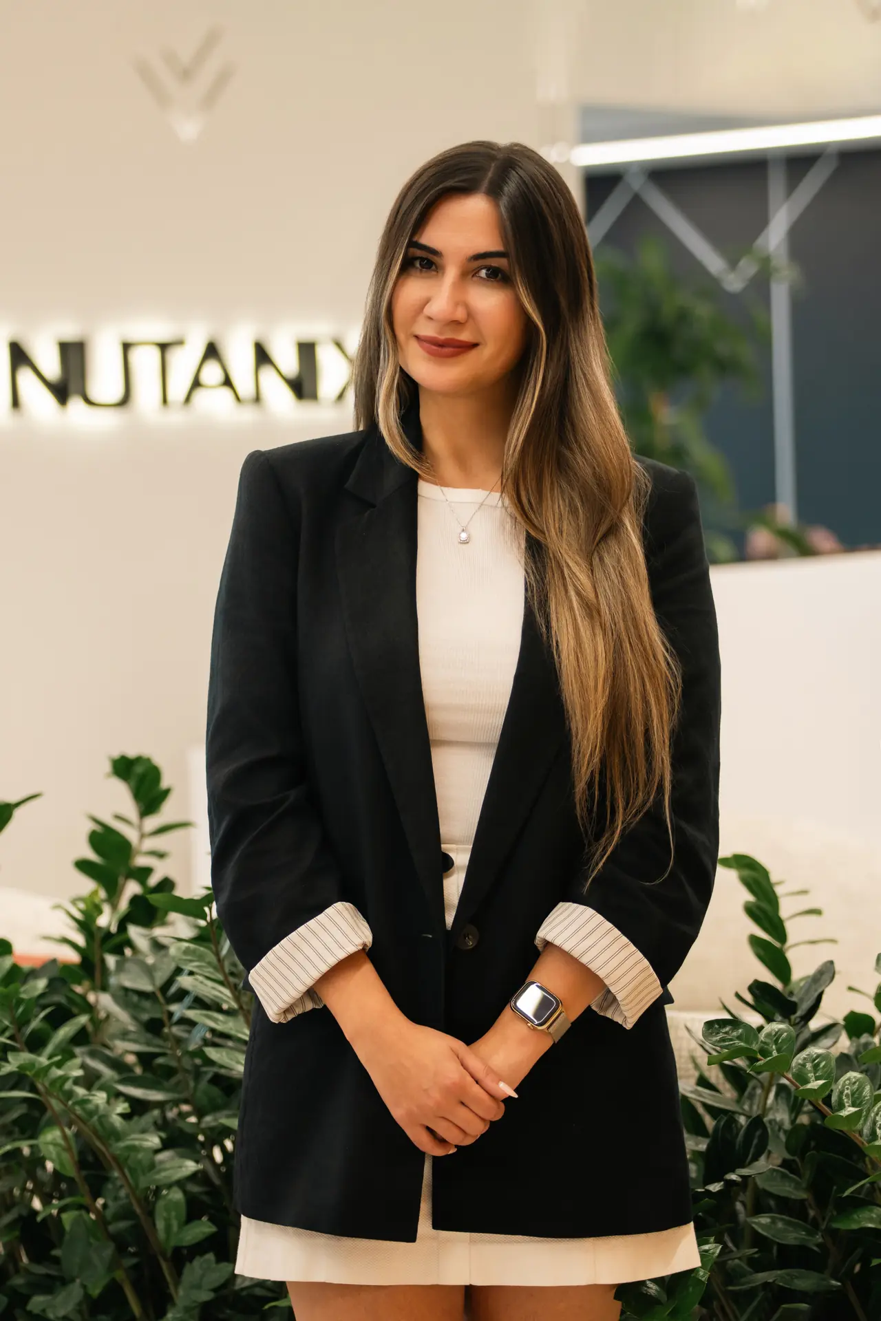 Standing portrait in a black blazer in front of the logo wall. On-site corporate headshot at the Nutanix office in Dubai.