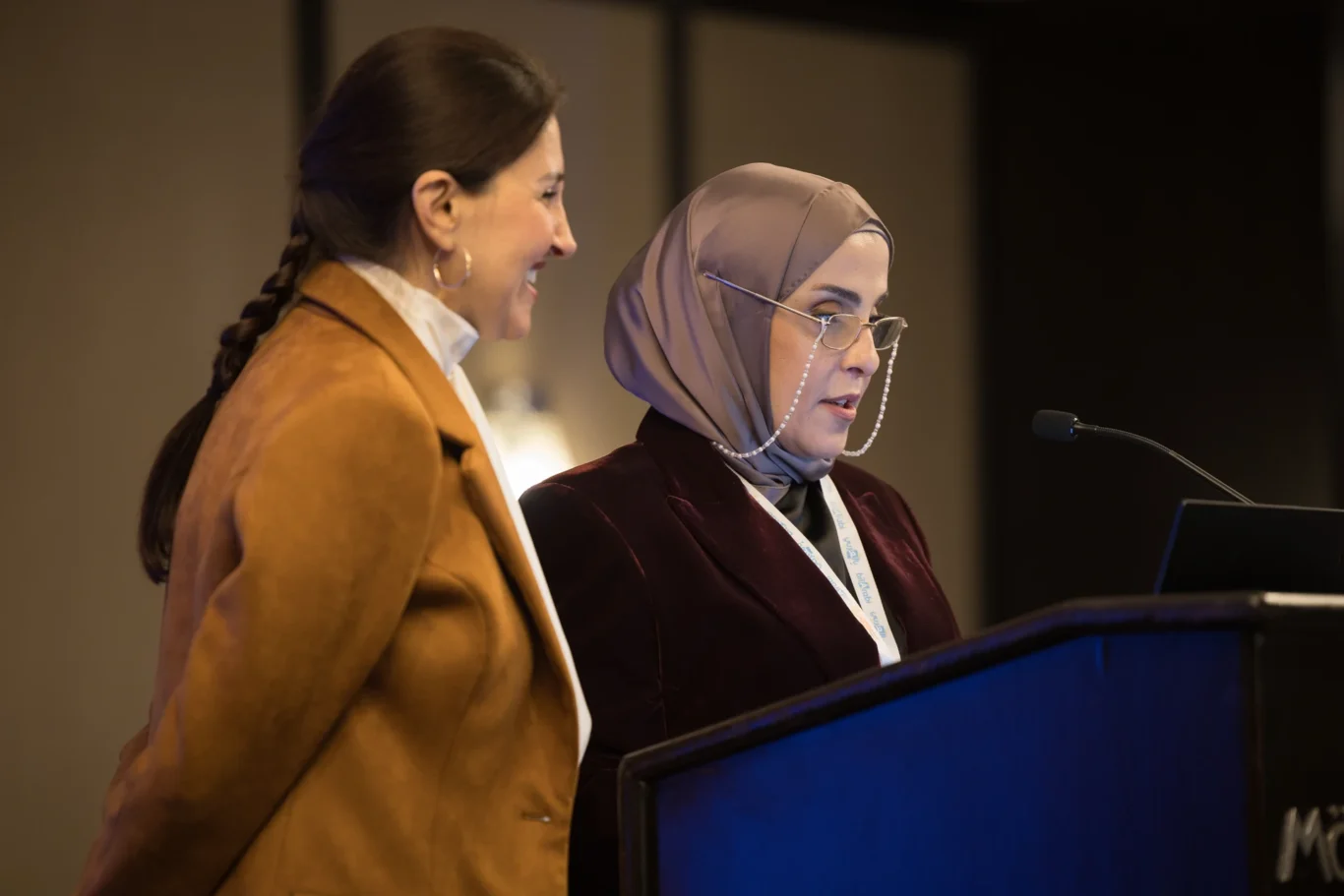 Two speakers sharing the podium during a presentation. Corporate event photography by MRPS for My Arabic Publishing at Movenpick Grand Al Bustan, Dubai.