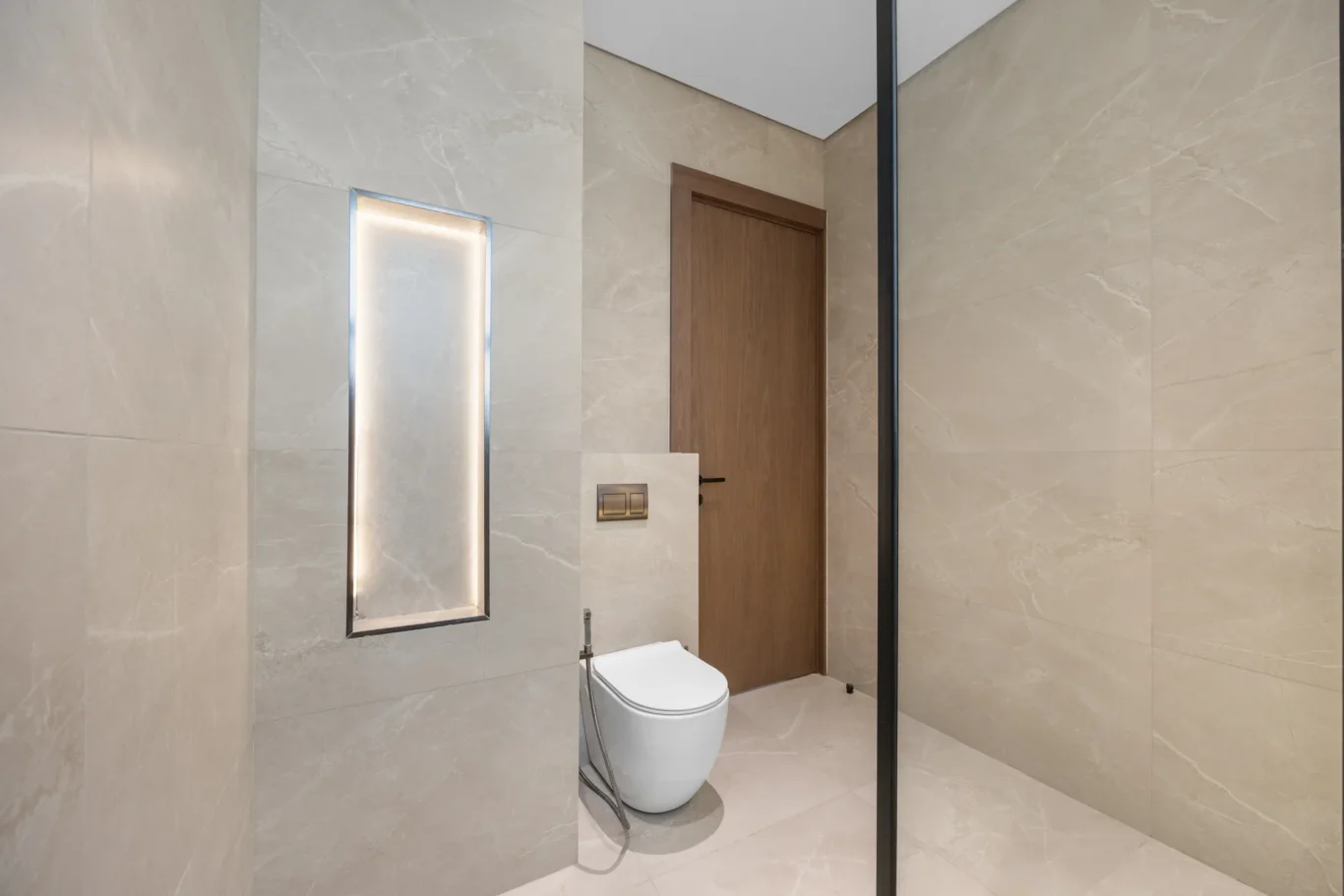 Bathroom with a lit wall niche and wall-hung toilet, unfurnished five-bedroom villa in Al Furjan, Dubai.