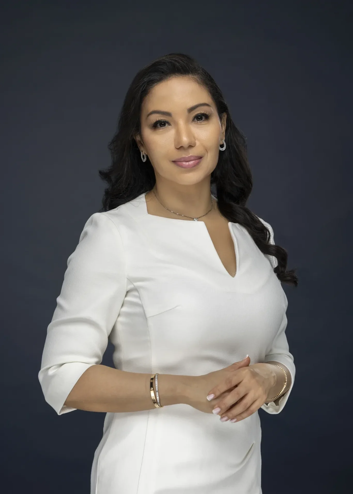 Three quarter portrait of Sandra in a white dress with arms crossed, navy backdrop. Business profile and LinkedIn portrait photography by MRPS in Dubai.