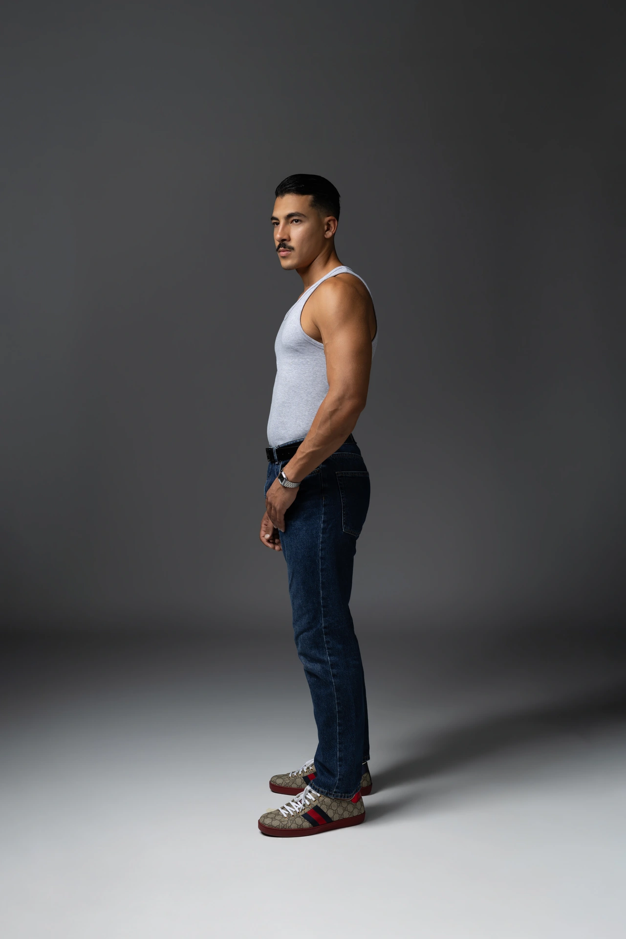Side profile digital in a white tank top and jeans, hands in pockets. Male modeling portfolio photoshoot by MRPS in Dubai, photographed by Nastaran.