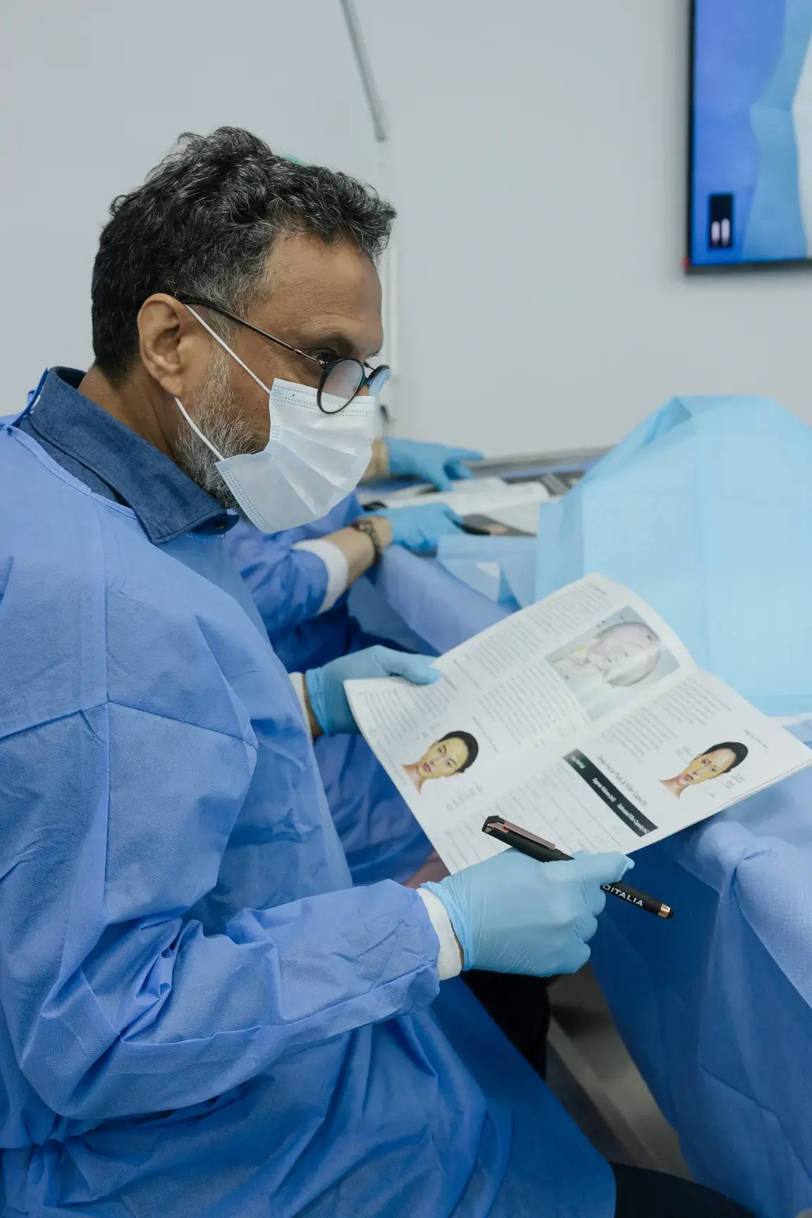 Doctor in a surgical gown reviewing the course notes. Event photography by MRPS at the Promoitalia Cadaver Lab medical anatomy course in Dubai.