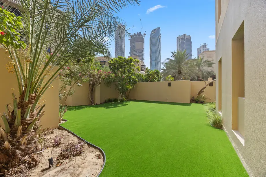Garden with palms and the Downtown skyline beyond in an unfurnished two-bedroom garden apartment in Old Town, Downtown Dubai, photographed for ELITE Property Brokerage.
