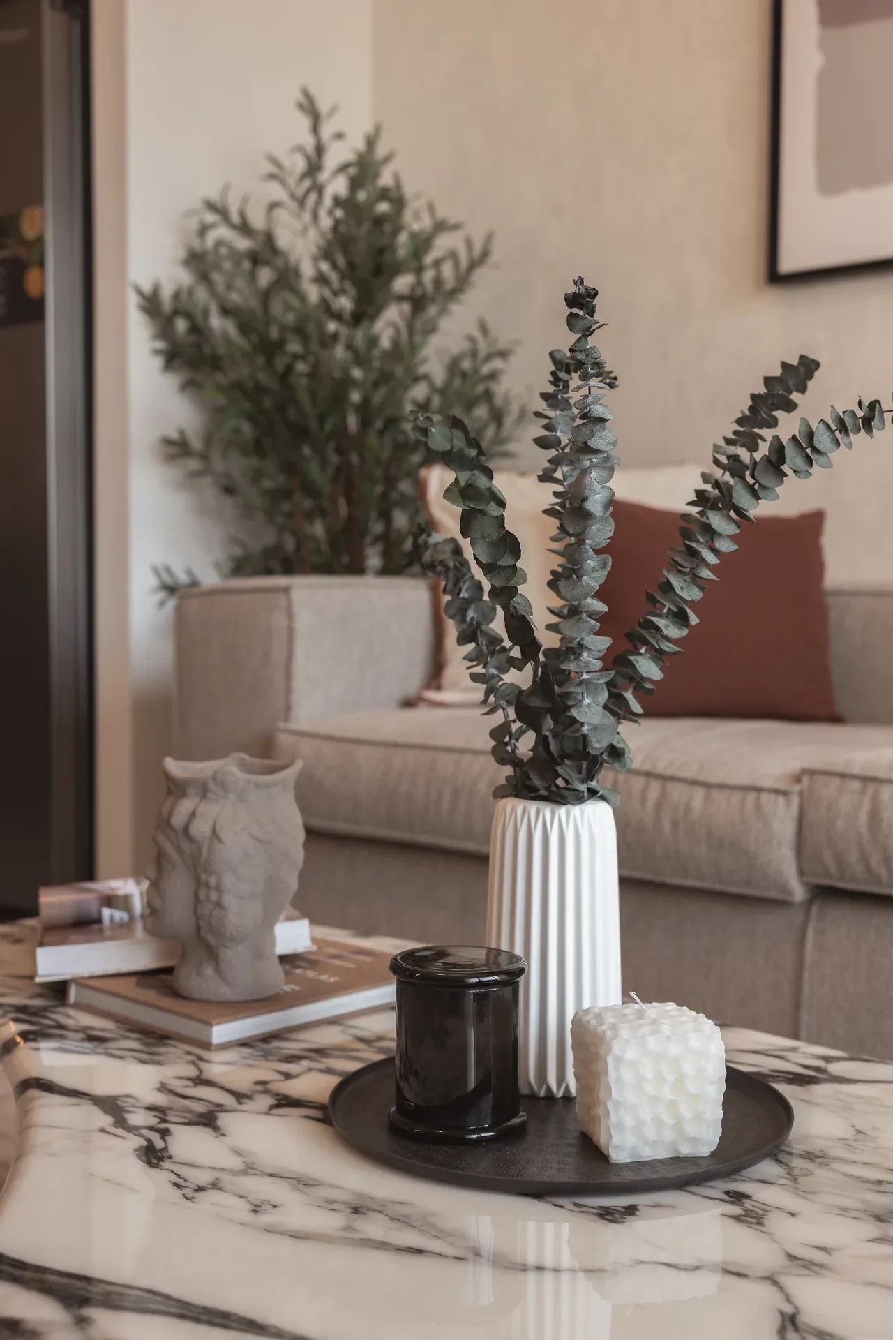 Marble coffee table with eucalyptus vase, candles and sculptural decor. Interior design photography for Aziza Home by MRPS in Dubai.