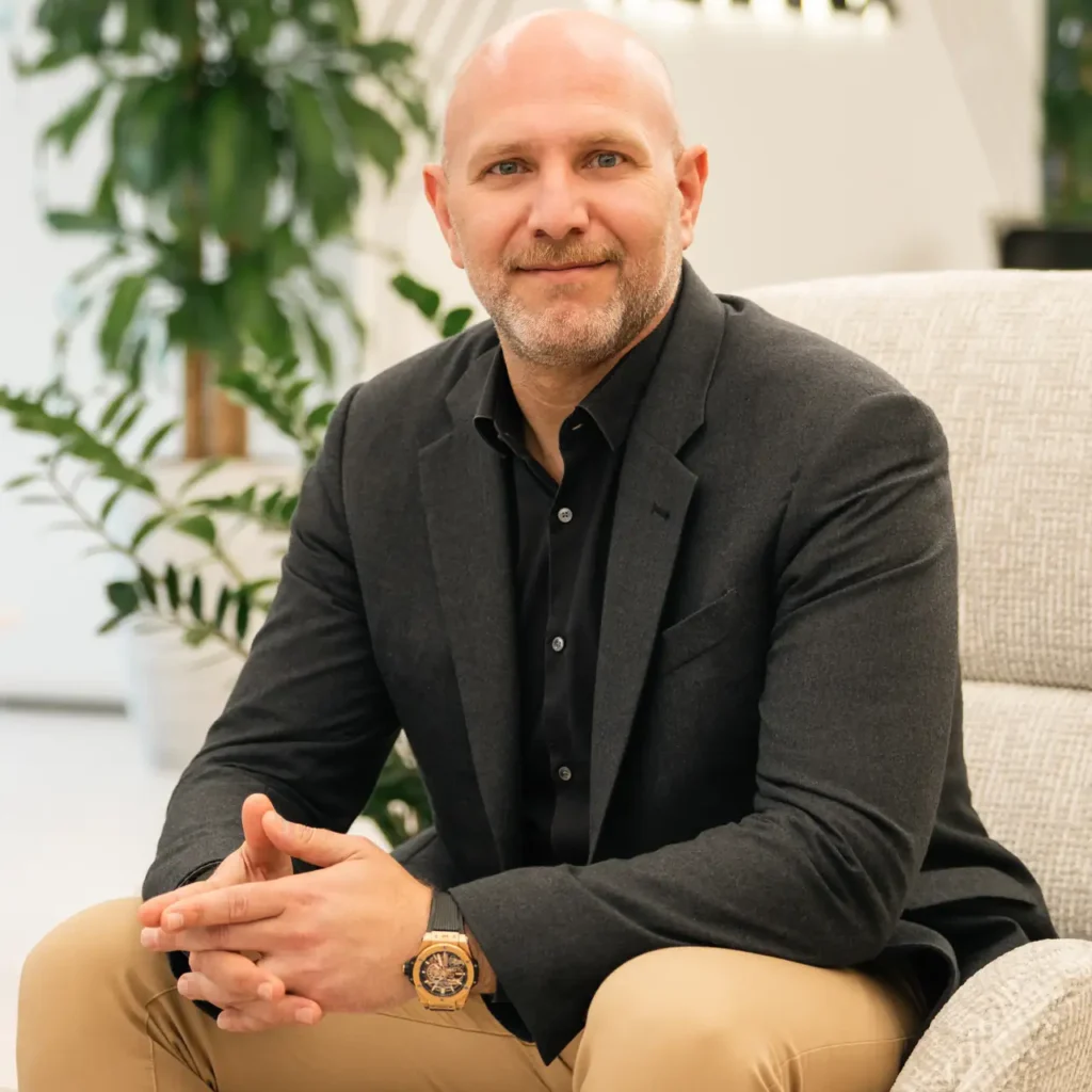 Senior leader seated in the office lounge with hands together. On-site corporate headshot at the Nutanix office in Dubai.