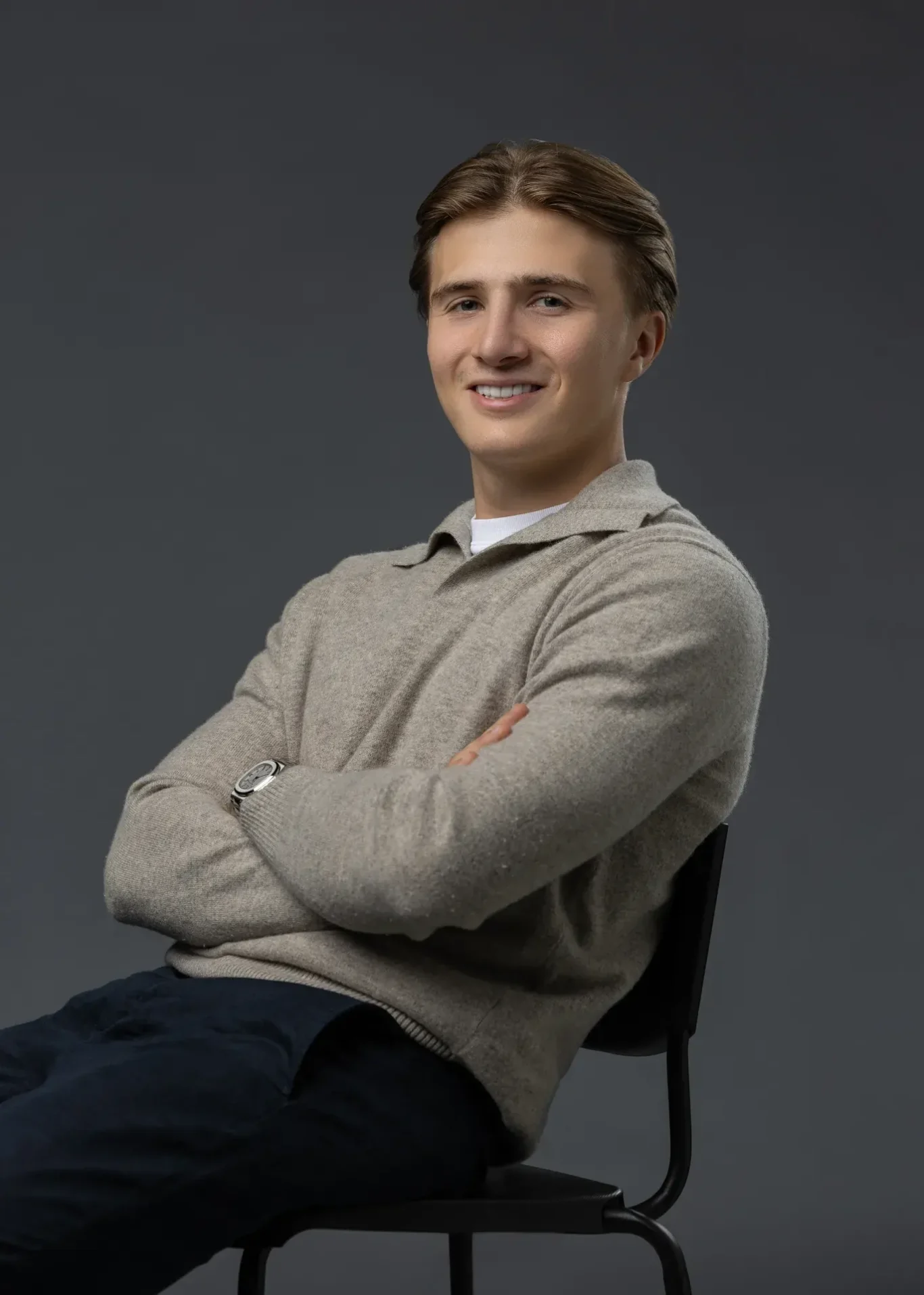 Smiling seated portrait with arms crossed in a beige sweater. Editorial business portrait by MRPS in Dubai for a financial magazine feature.