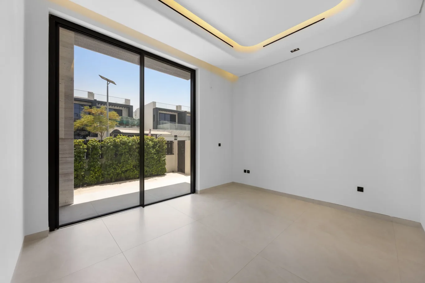 Ground floor bedroom with sliding doors to the garden, unfurnished five-bedroom villa in Al Furjan, Dubai.