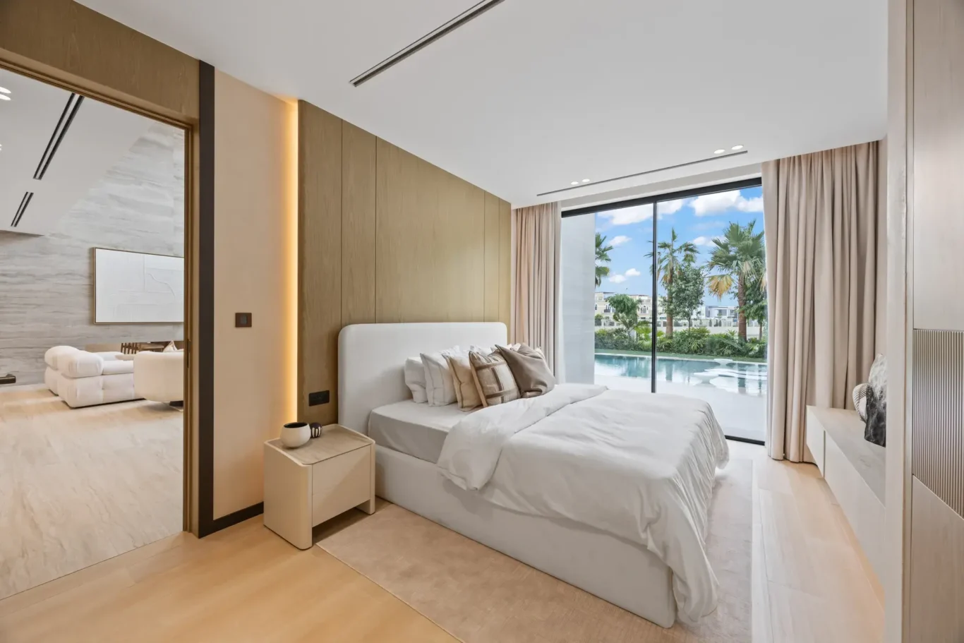 Ground floor bedroom with a white bed and a view of the pool, luxury villa in Jumeirah Islands, Dubai.