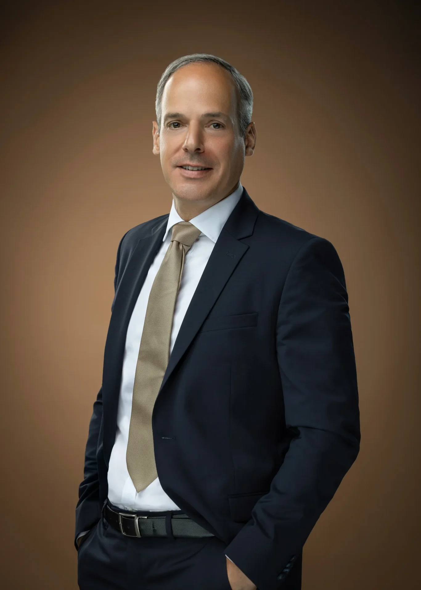 Relaxed leadership portrait with hand in pocket on a warm brown backdrop. Corporate business portrait of a Dubai CEO, photographed at the MRPS studio in Business Bay.