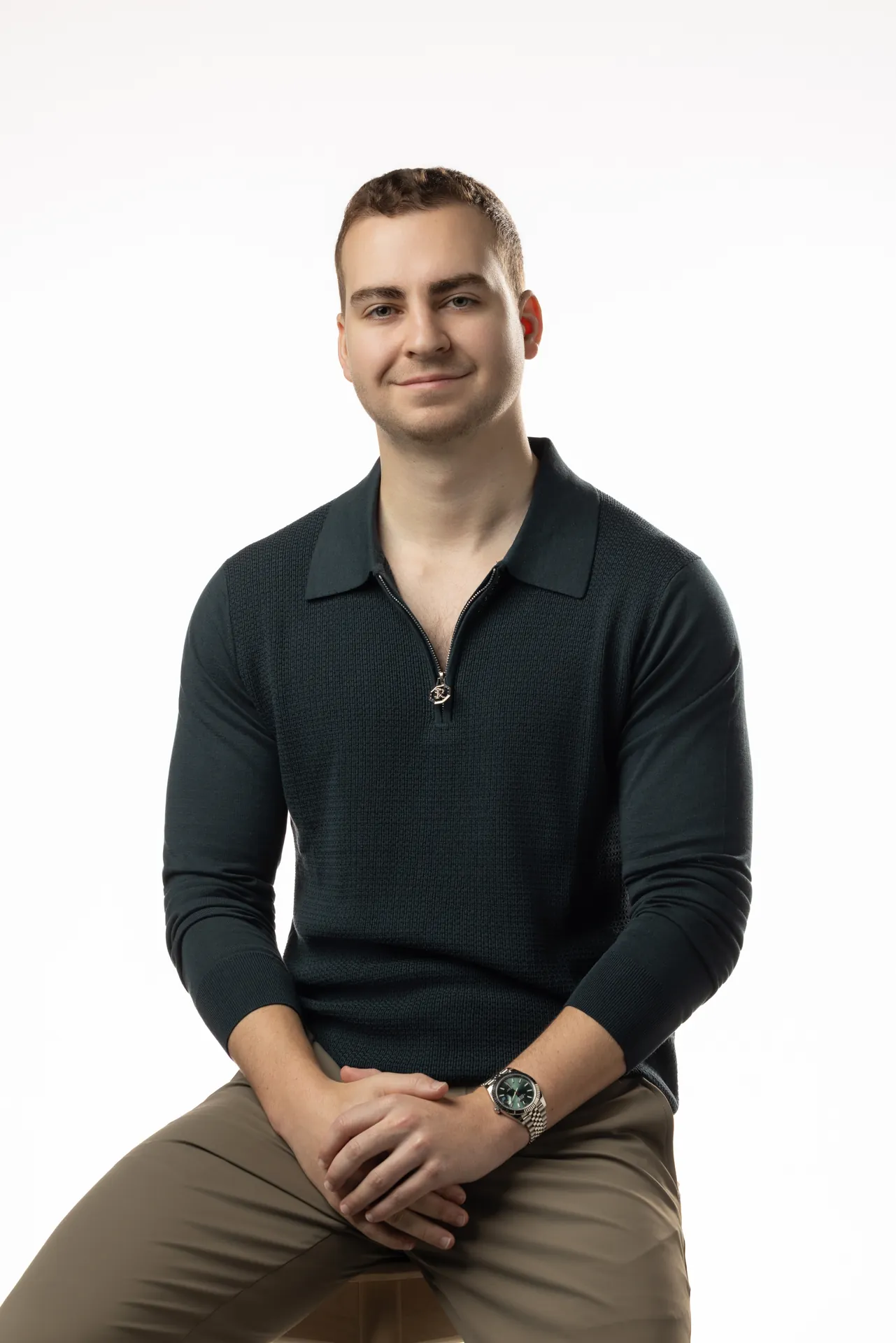 Seated portrait in a dark knit polo on a clean white backdrop. Professional headshot of Tim Ruscica of Tech With Tim, photographed at the MRPS studio in Dubai.