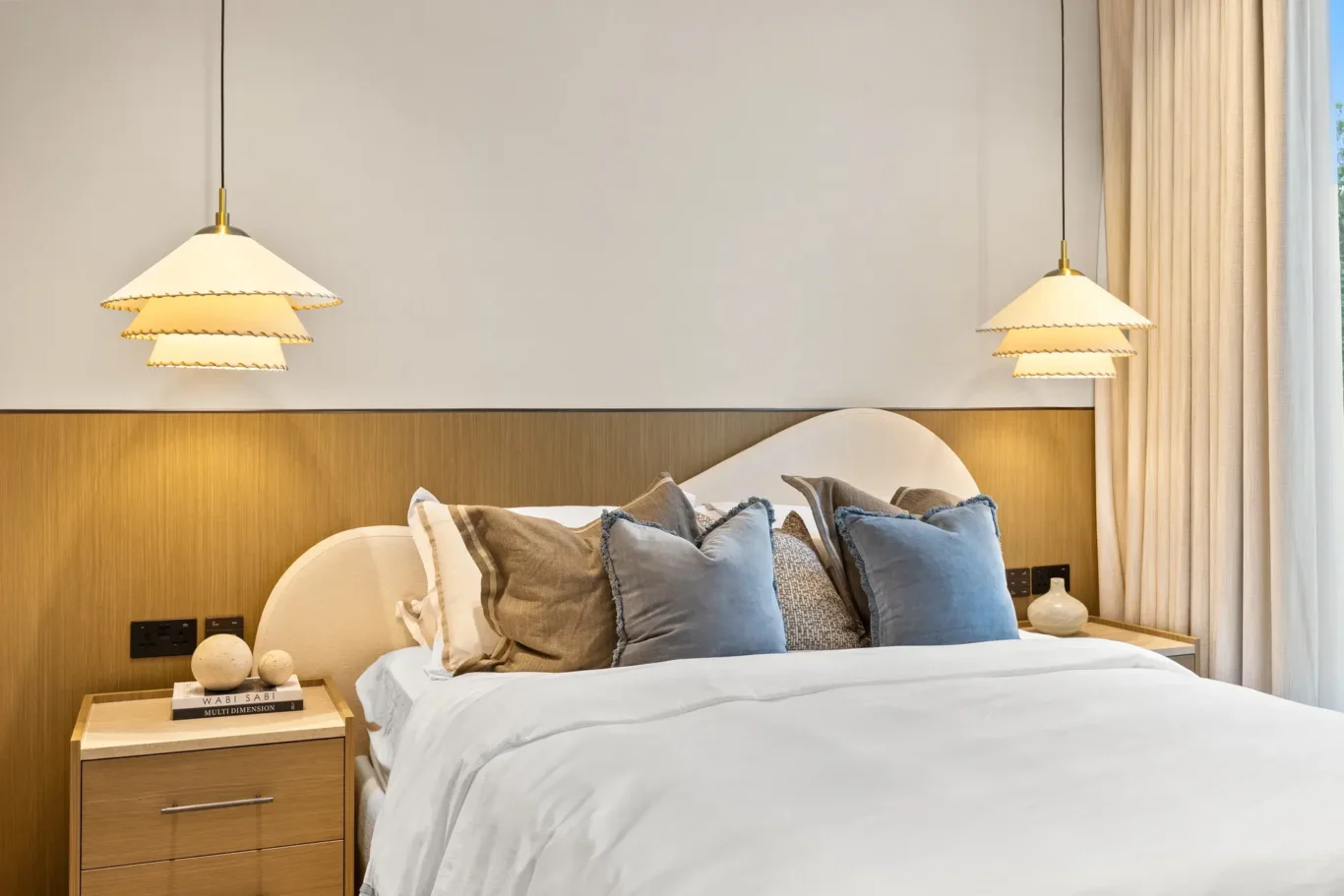 Bed with blue cushions and pleated pendant lamps, luxury villa in Jumeirah Islands, Dubai.