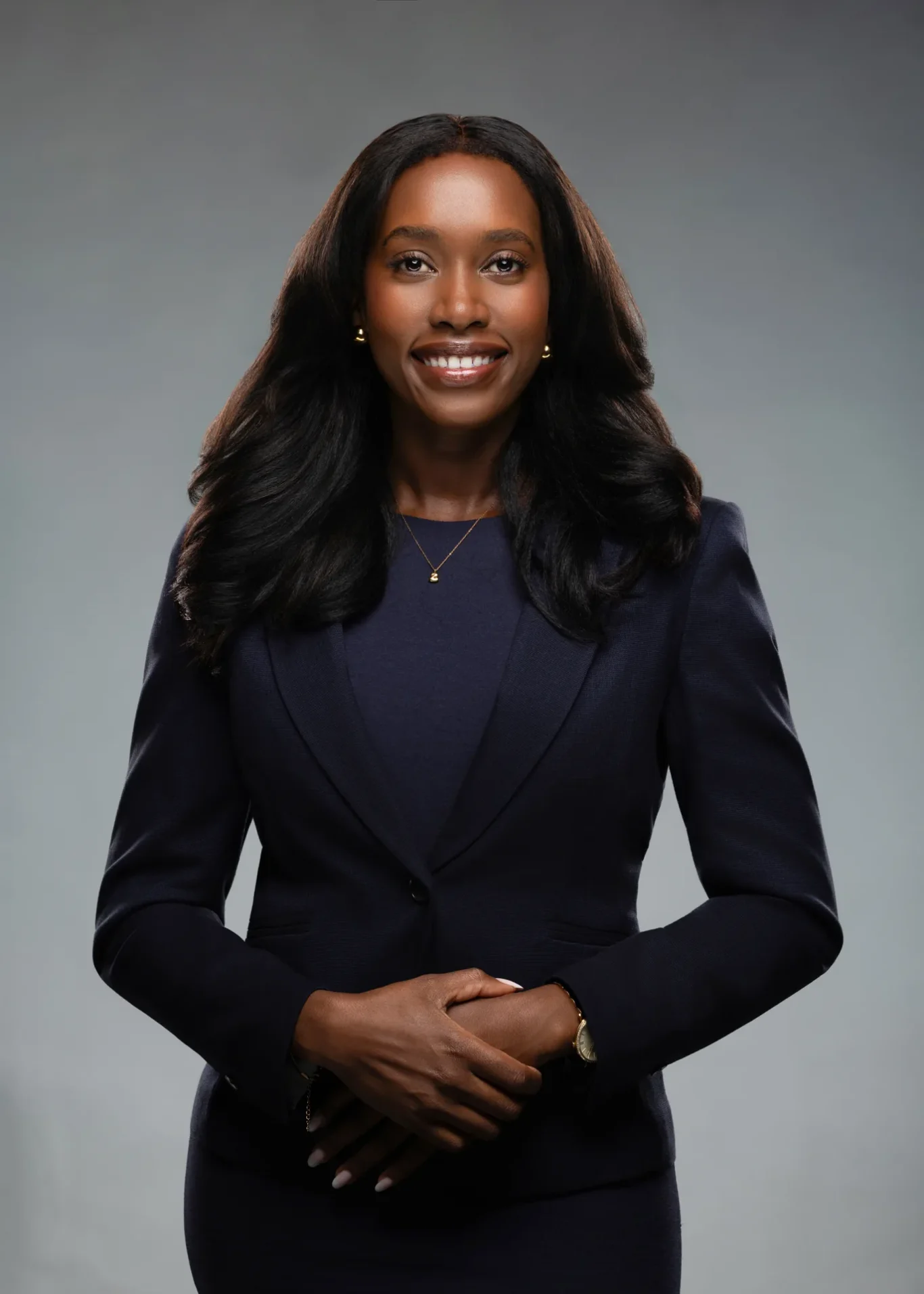 Businesswoman headshot in a navy blazer with hands together. Photographed at the MRPS studio in Business Bay, Dubai.