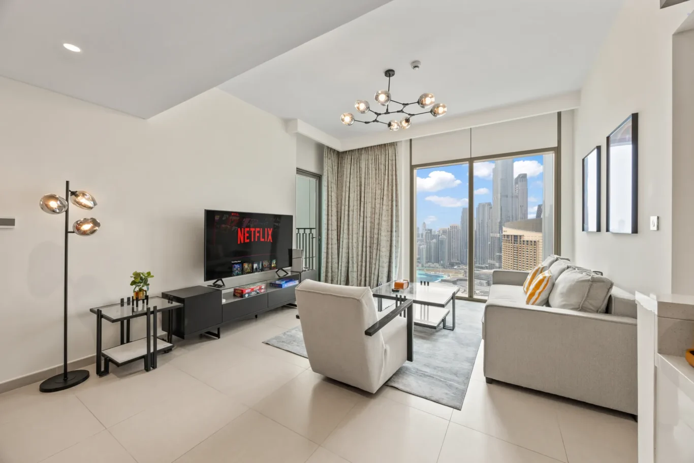 Grey sofa and coffee table facing the floor to ceiling windows. Day, twilight and night Airbnb photography by MRPS for Vista Haus Holiday Homes in Downtown Dubai.