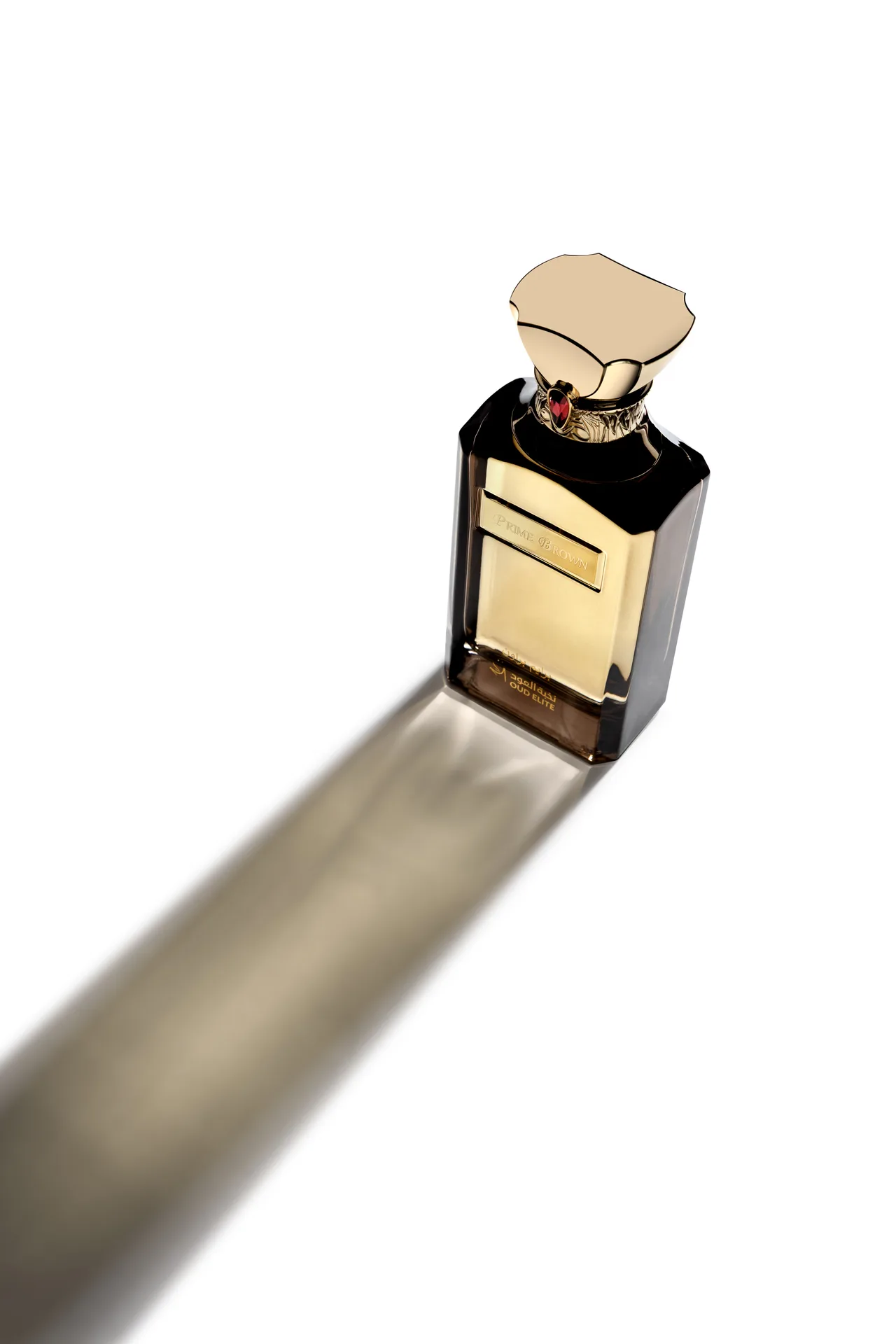 High-angle shot of the Oud Elite Prime Brown perfume bottle with a sculpted gold cap and a long golden shadow.