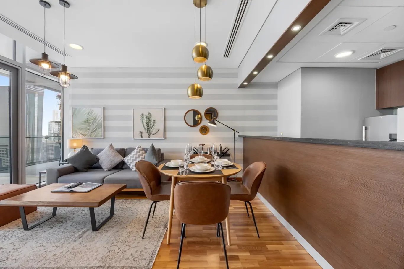 Dining table and lounge with pendant lights in a Your Stay Apartments one-bedroom at Burj Daman, DIFC, Dubai.