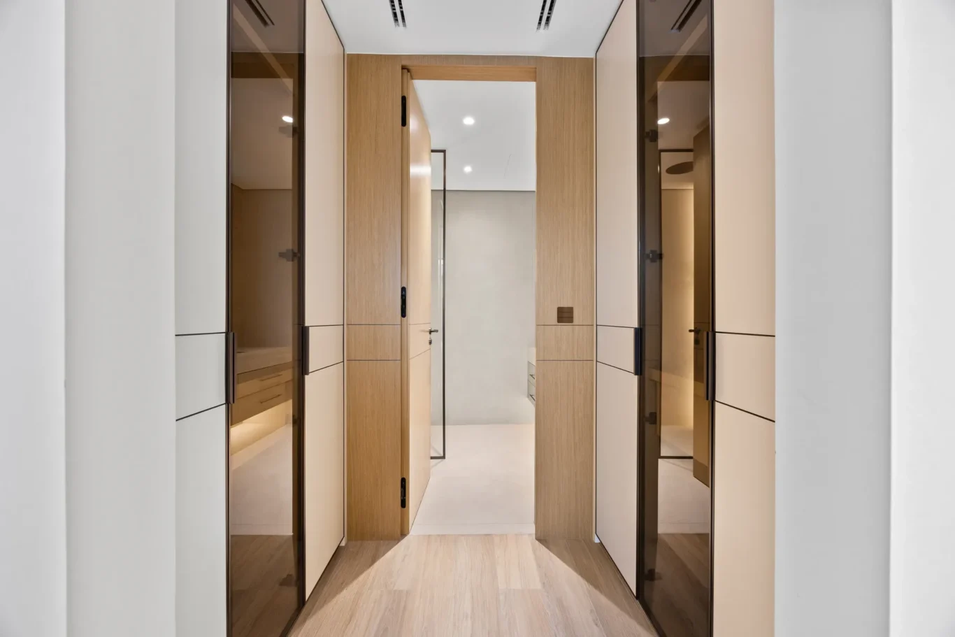 Walk-in wardrobe corridor with wood and glass closets, luxury villa in Jumeirah Islands, Dubai.