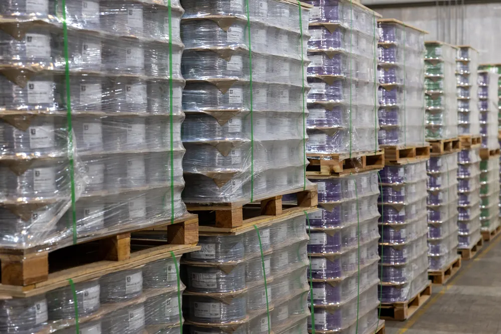 Close view of wrapped pallets of purple and grey B3 International cable reels ready for delivery.