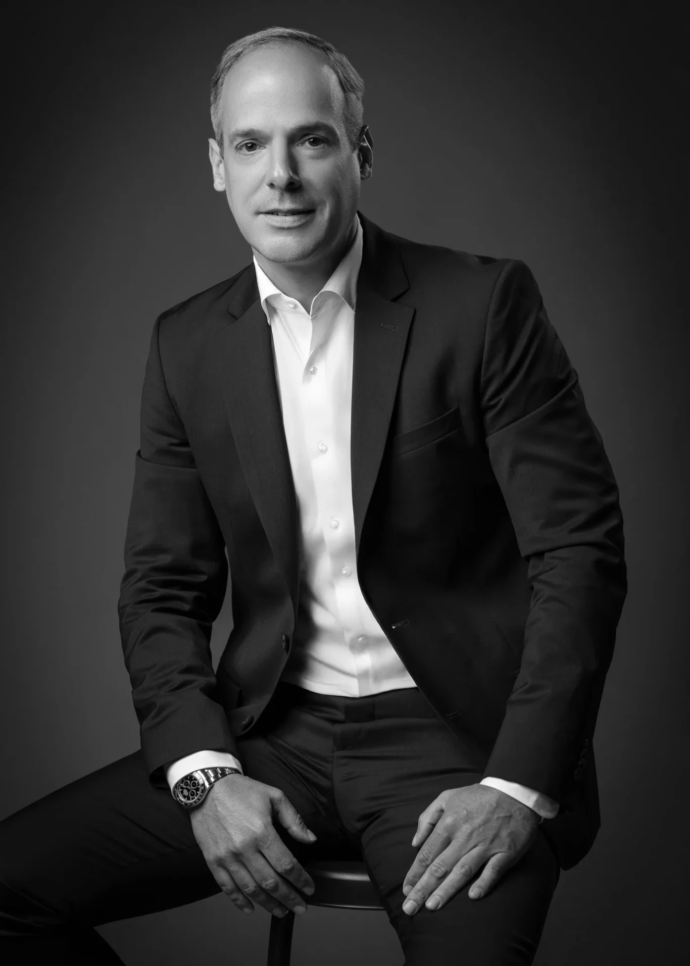 Black and white full seated portrait on a studio stool. Corporate business portrait of a Dubai CEO, photographed at the MRPS studio in Business Bay.
