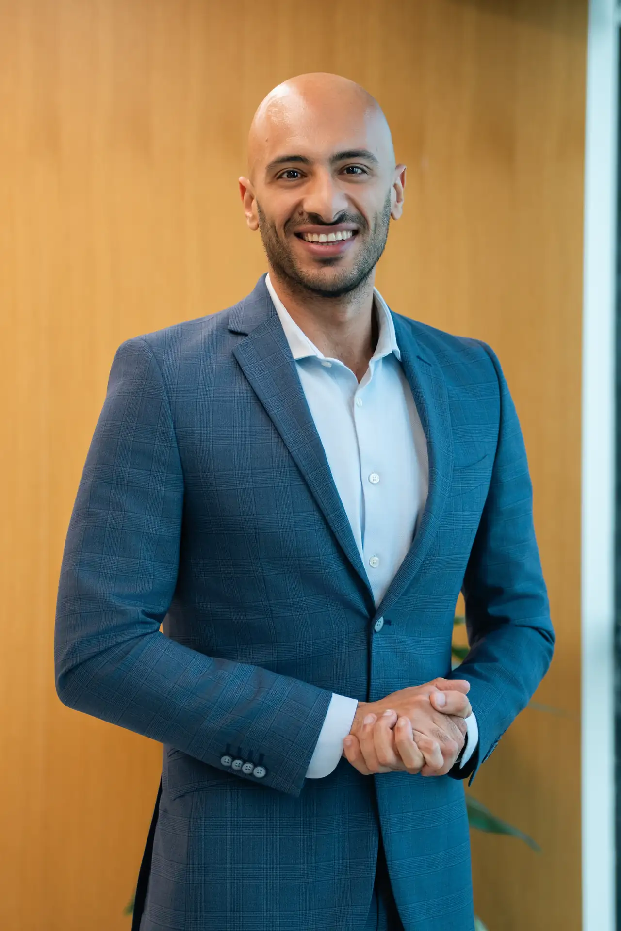 Executive in a blue suit against warm wood panelling. On-site corporate headshot at the Nutanix office in Dubai.