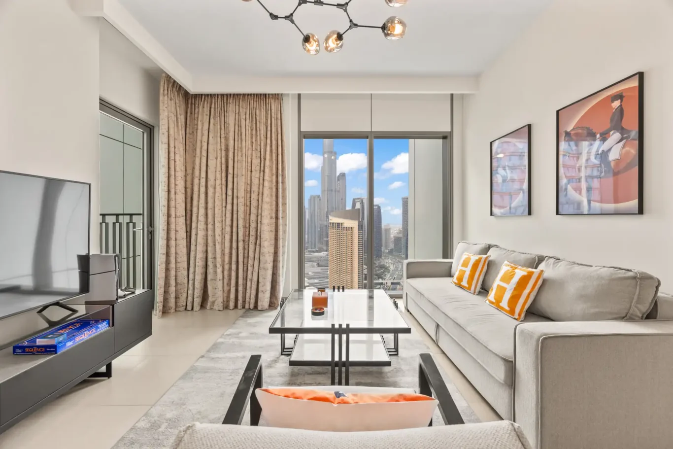 Living room with the TV wall, art prints and chandelier. Day, twilight and night Airbnb photography by MRPS for Vista Haus Holiday Homes in Downtown Dubai.