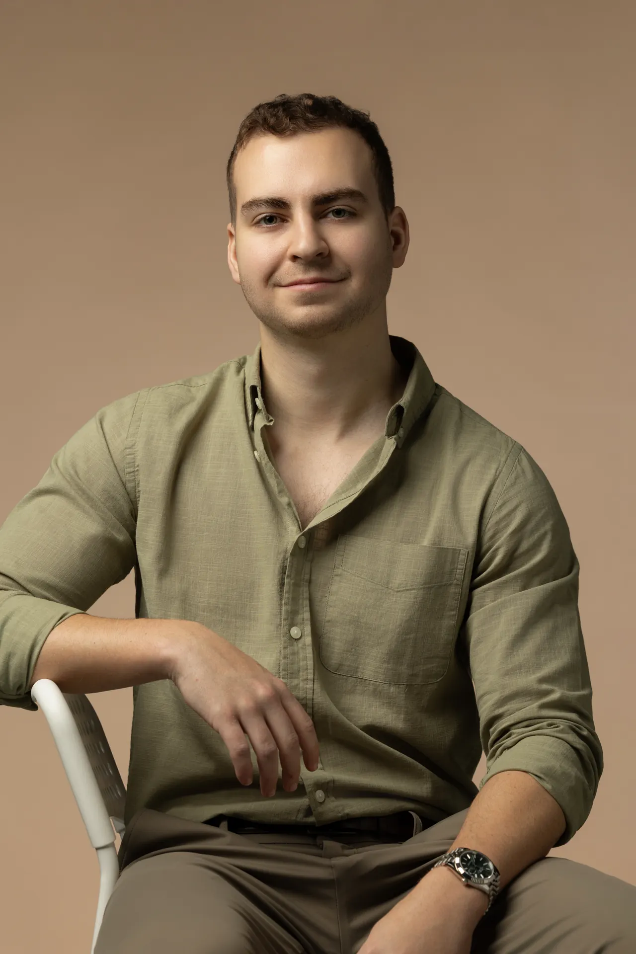 Seated chair pose in an olive shirt on a beige backdrop. Professional headshot of Tim Ruscica of Tech With Tim, photographed at the MRPS studio in Dubai.