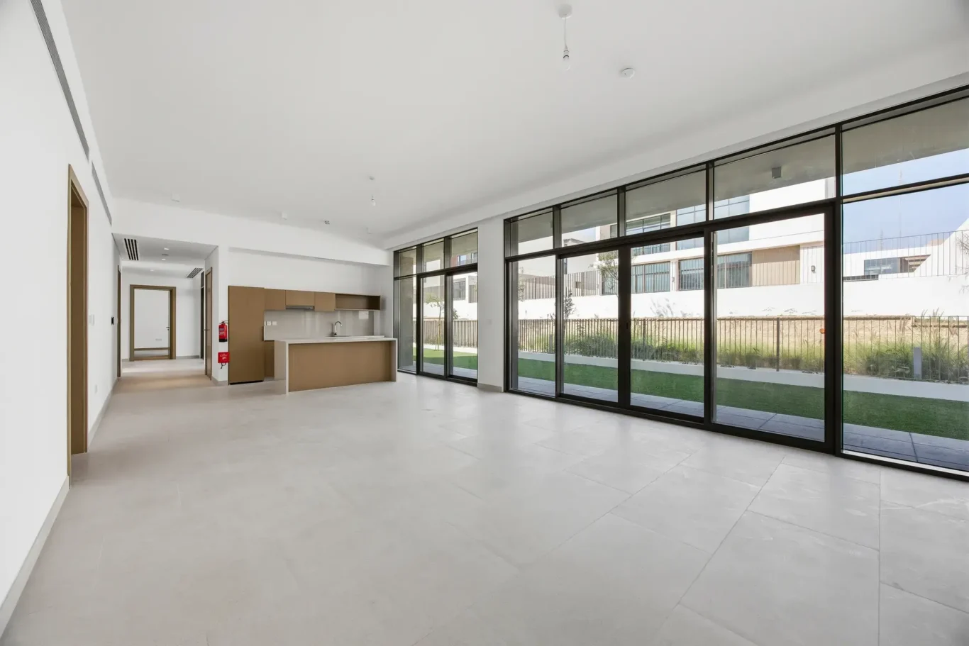 Open plan living and dining space with floor to ceiling glass doors to the garden. Villa photography by MRPS in Dubai for ELITE Property Brokerage.