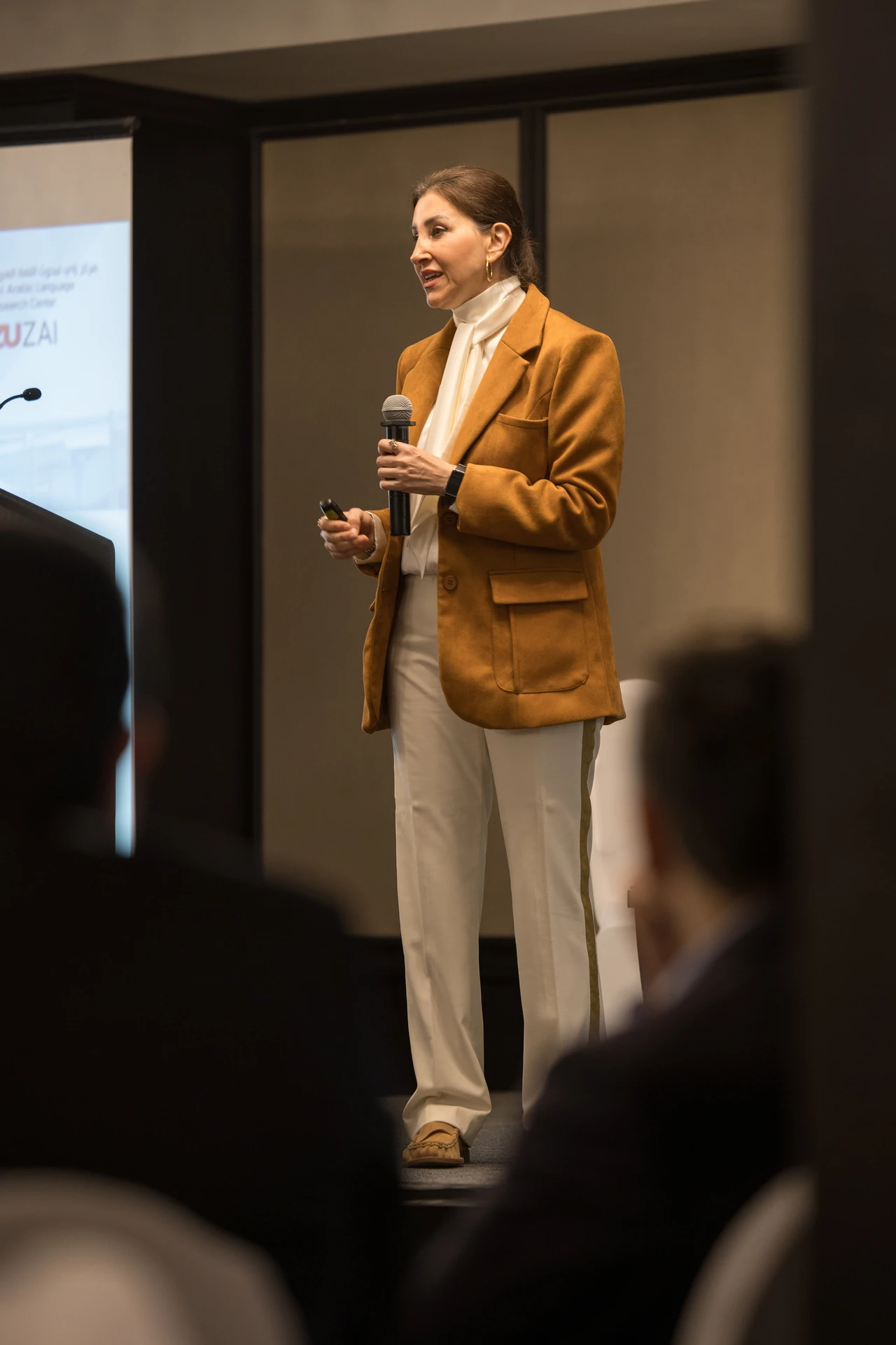 Speaker with a handheld microphone addressing the room from the floor. Corporate event photography by MRPS for My Arabic Publishing at Movenpick Grand Al Bustan, Dubai.