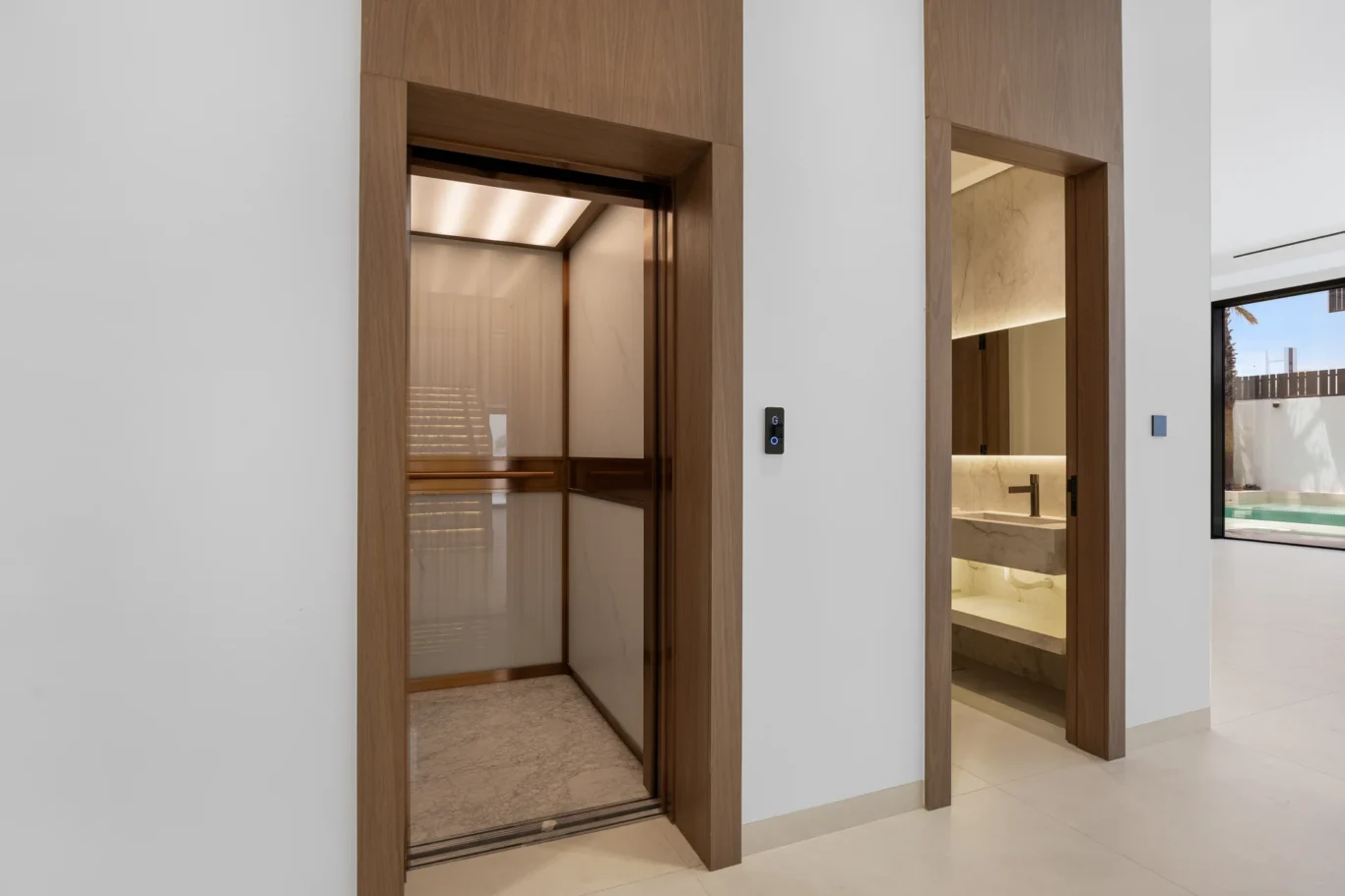 Private lift with walnut surround beside the guest bathroom, unfurnished five-bedroom villa in Al Furjan, Dubai.