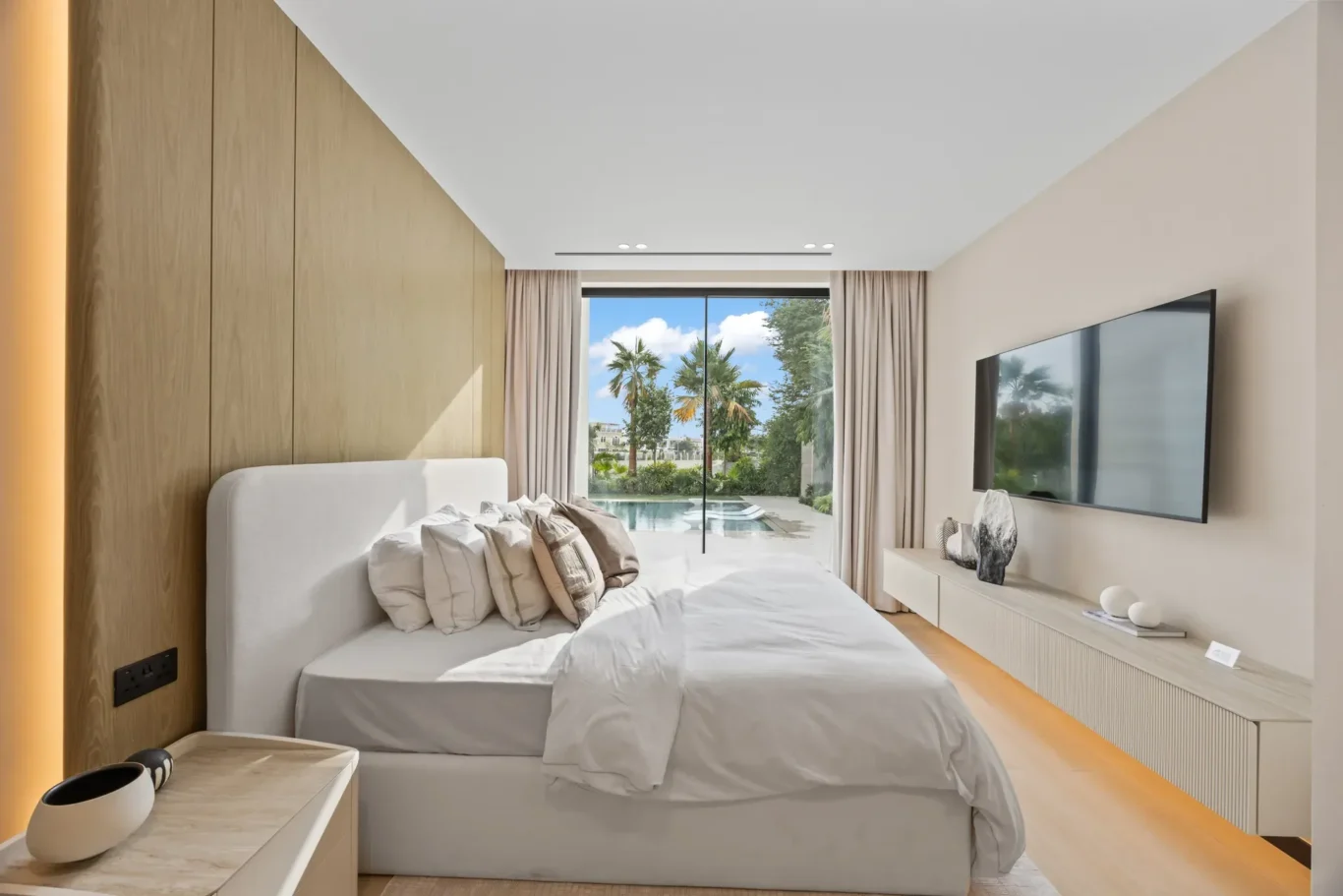 Ground floor bedroom with a wall-mounted TV and garden view, luxury villa in Jumeirah Islands, Dubai.
