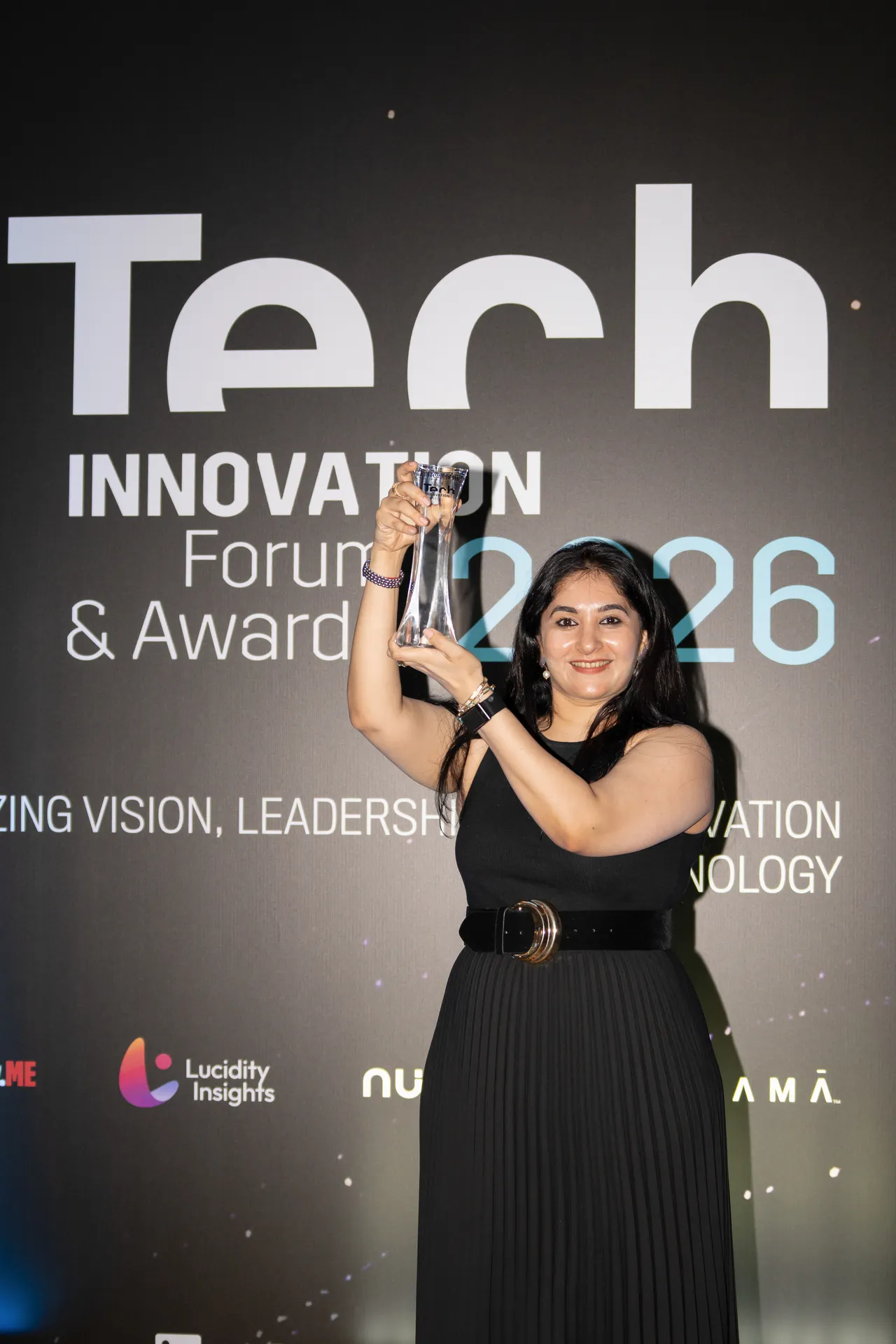 Winner raising her trophy at the awards backdrop. Event photography by MRPS for FundedNext at the Tech Innovation Awards 2026, Al Habtoor Palace, Dubai.