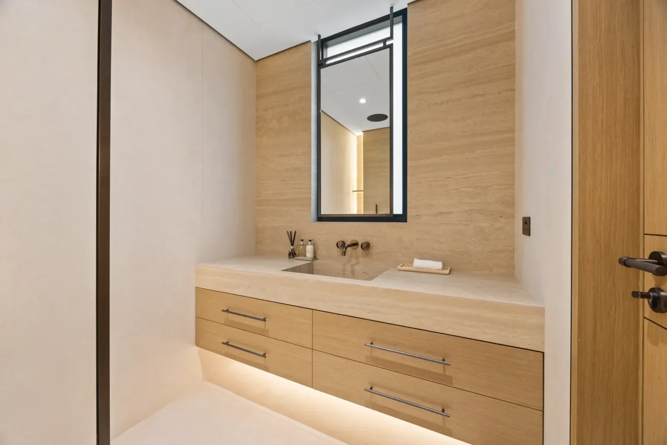 En-suite vanity with wood drawers and a framed mirror, luxury villa in Jumeirah Islands, Dubai.