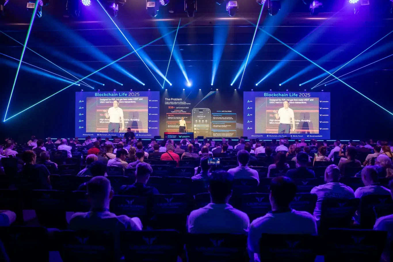 Main stage with blue stage lighting and LED screens. Event photography by MRPS at Blockchain Life 2025, Festival Arena, Dubai.