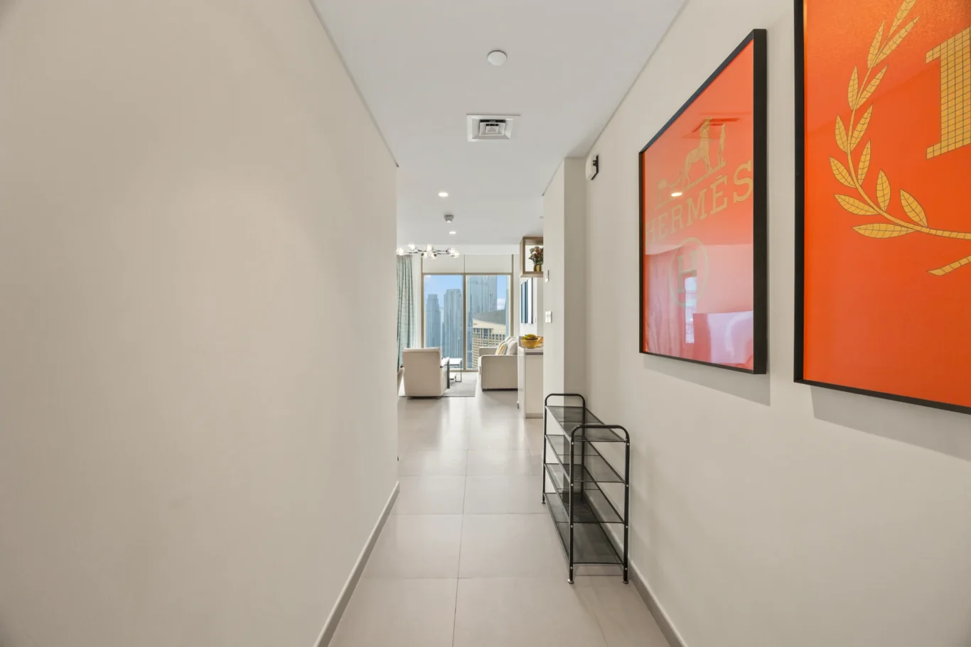 Entrance hallway with orange wall art and black console. Day, twilight and night Airbnb photography by MRPS for Vista Haus Holiday Homes in Downtown Dubai.
