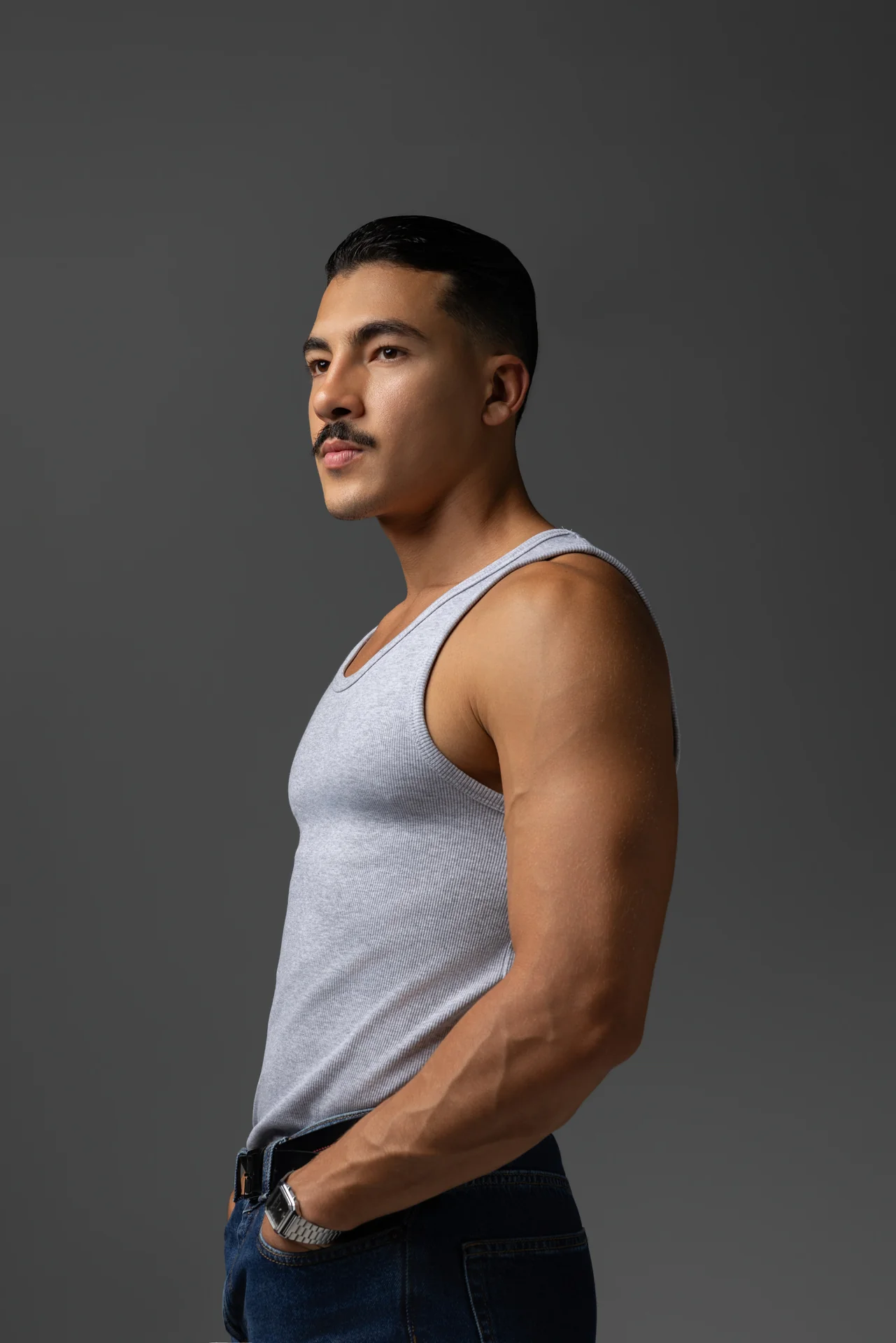 Three quarter portrait in a grey ribbed tank top, looking to the side. Male modeling portfolio photoshoot by MRPS in Dubai, photographed by Nastaran.