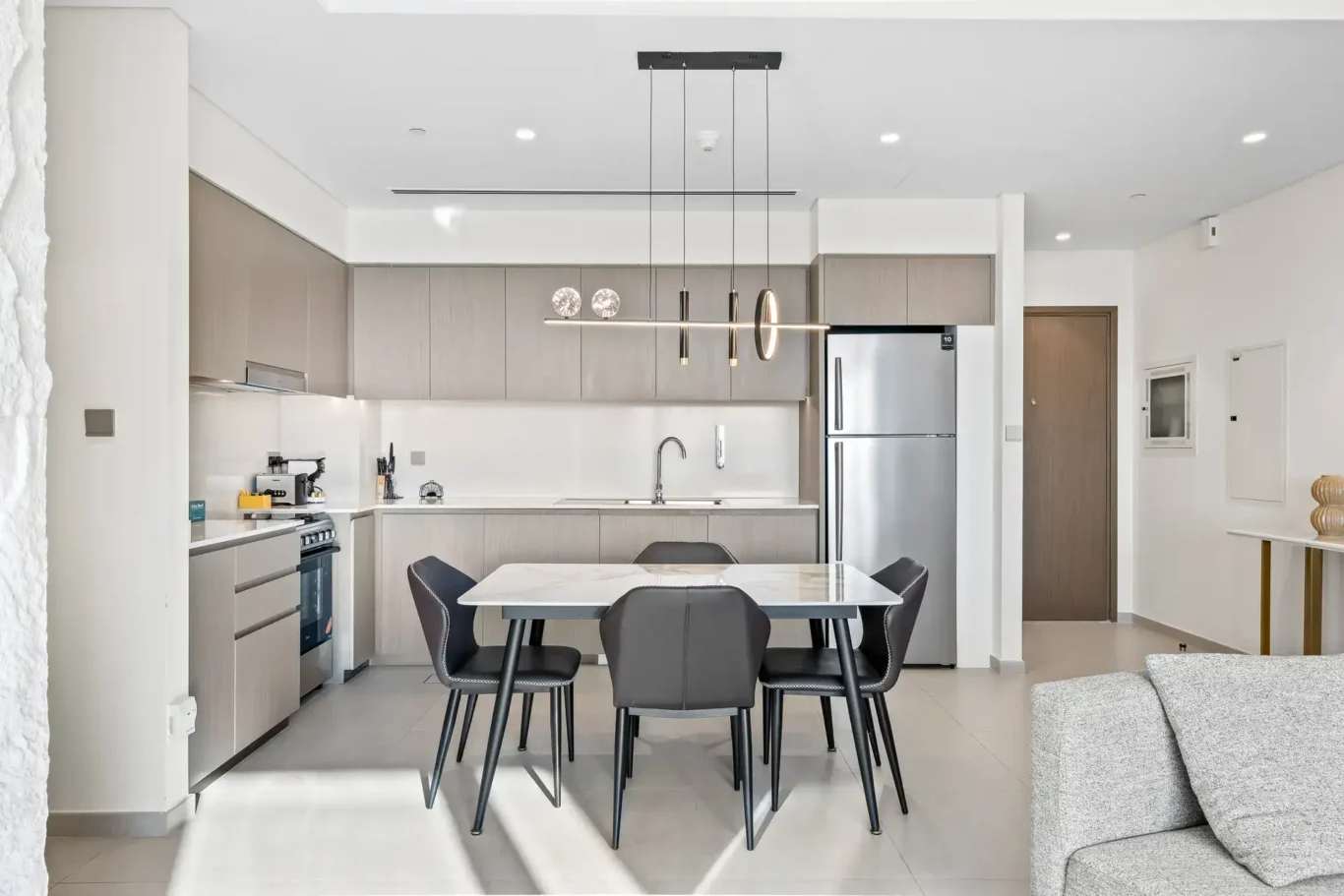 Wide view of the kitchen with stainless steel fridge and the dining table. Airbnb photography by MRPS for Solea Stay in Dubai.