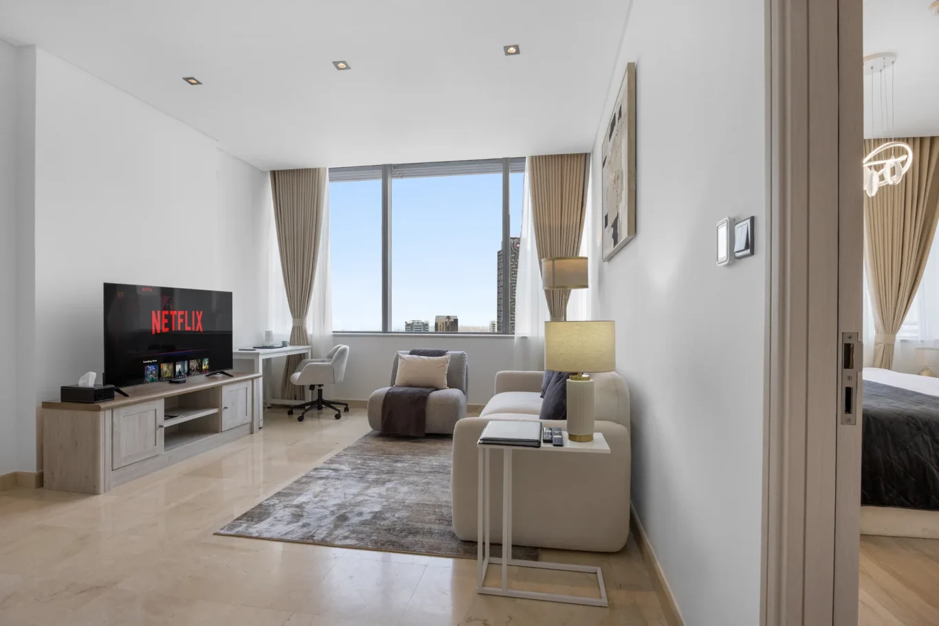 Living room overview with TV and dining area in a Your Stay Apartments one-bedroom at Sky Gardens, DIFC, Dubai.