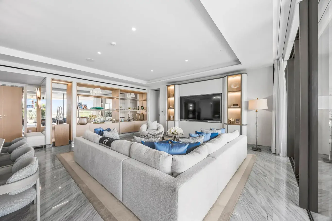 Living room with sectional sofa, TV wall and garden view in a furnished three-bedroom residence at Atlantis The Royal, Palm Jumeirah, photographed for Apex Homes Real Estate.