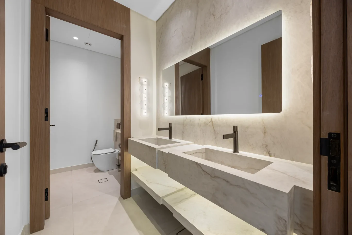 Guest bathroom with a marble double basin and backlit mirror, unfurnished five-bedroom villa in Al Furjan, Dubai.