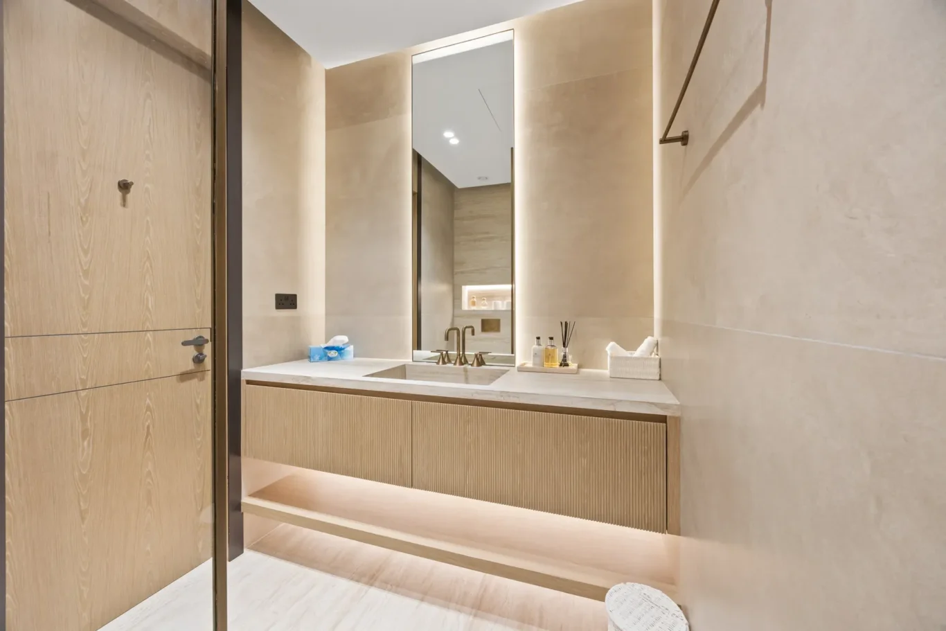 En-suite bathroom vanity with a lit mirror and wood cabinetry, luxury villa in Jumeirah Islands, Dubai.