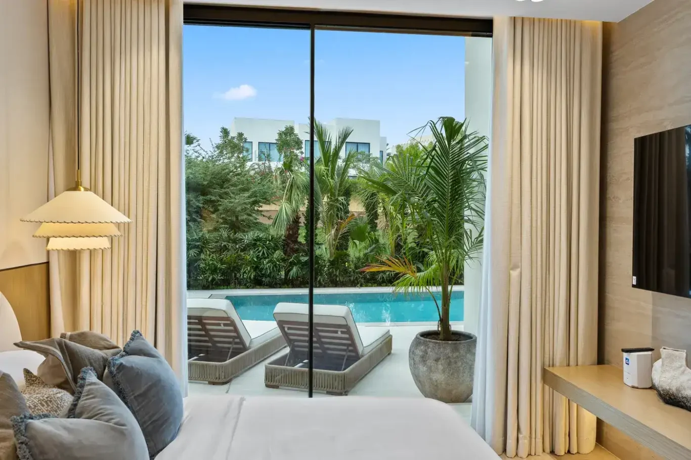Bedroom sliding doors opening onto the pool terrace and sun loungers, luxury villa in Jumeirah Islands, Dubai.