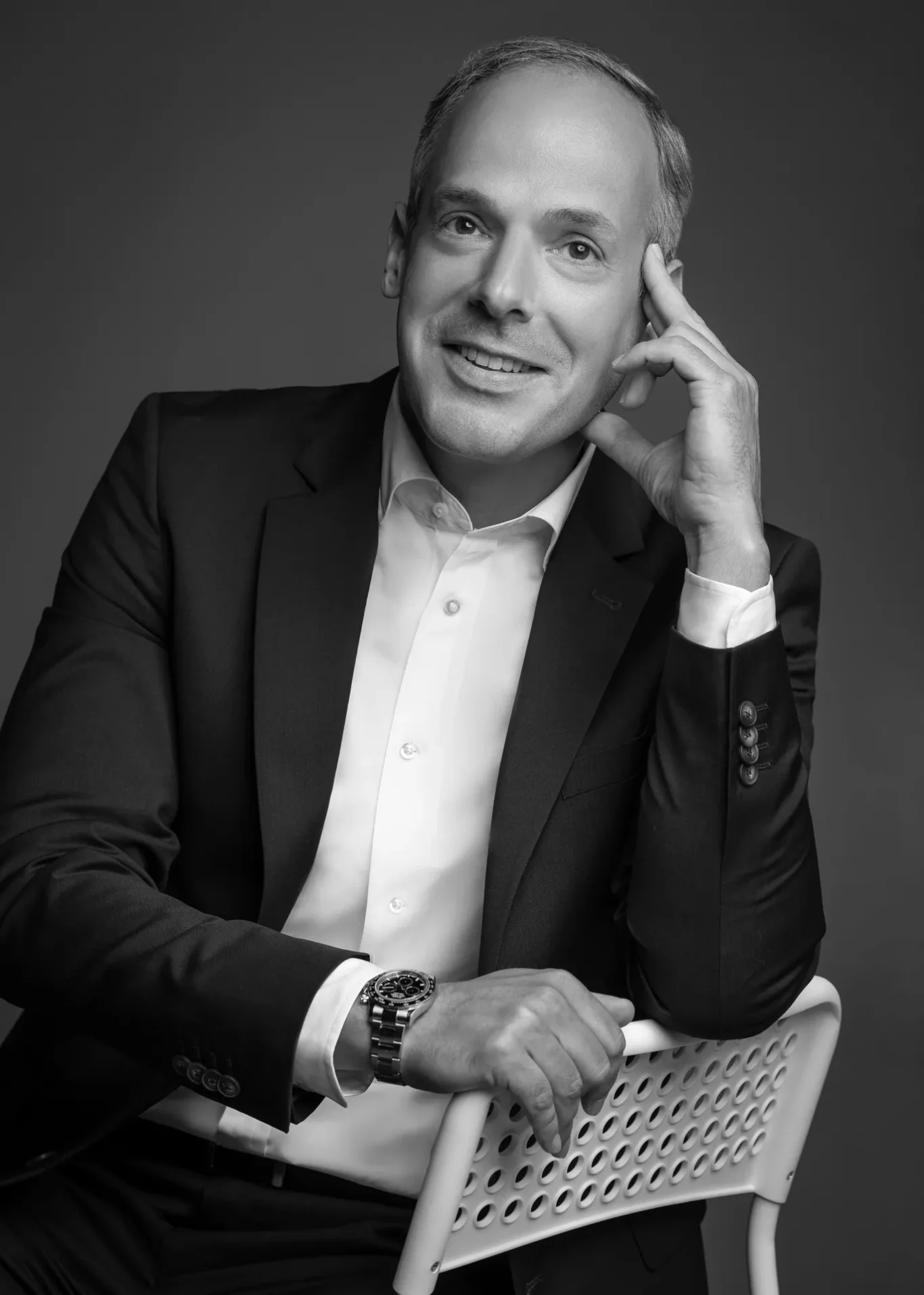 Black and white relaxed chair pose with hand at temple. Corporate business portrait of a Dubai CEO, photographed at the MRPS studio in Business Bay.