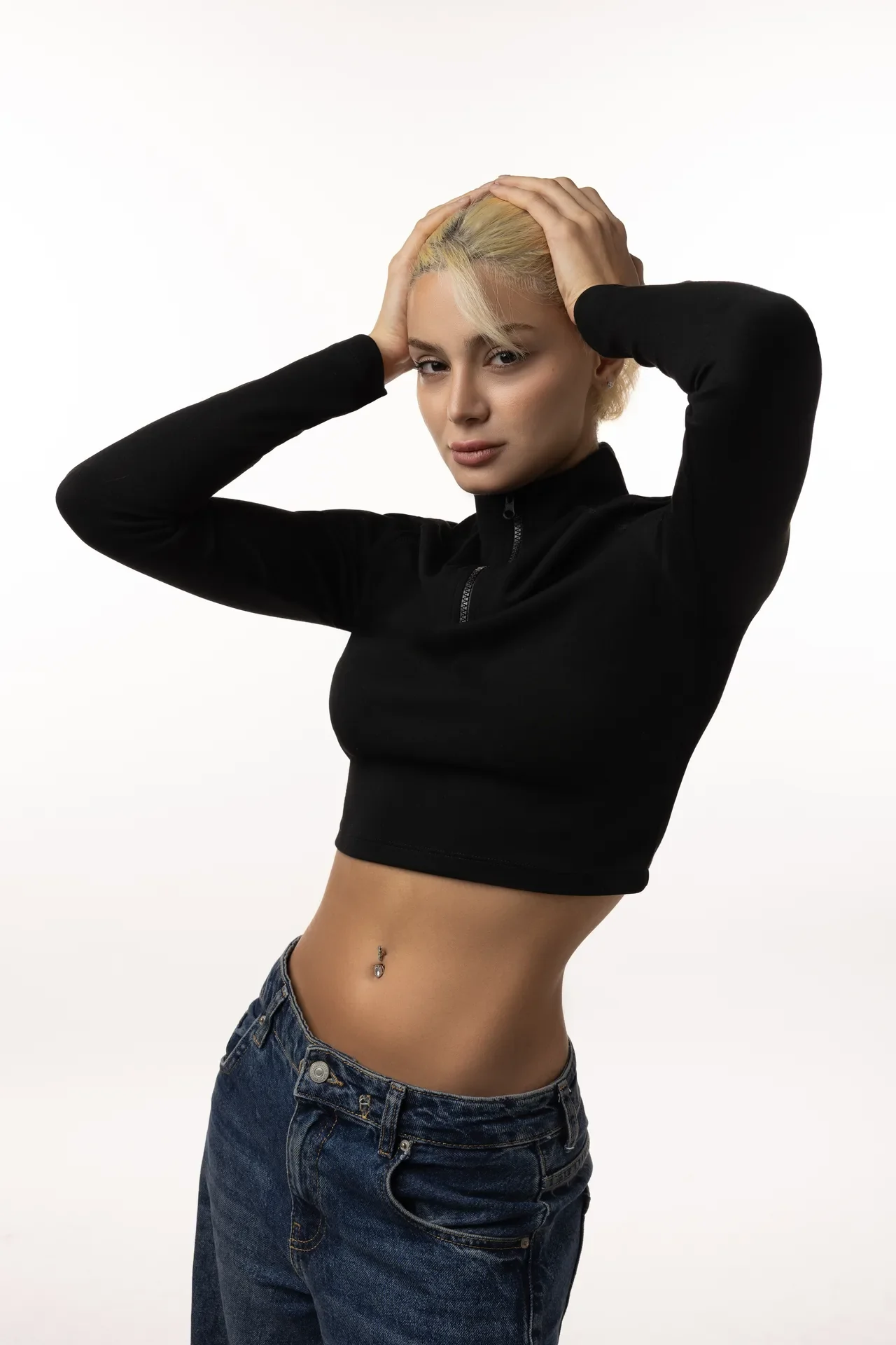 Dr. Aysan Soleymani in a black crop top and jeans with both hands in her hair.