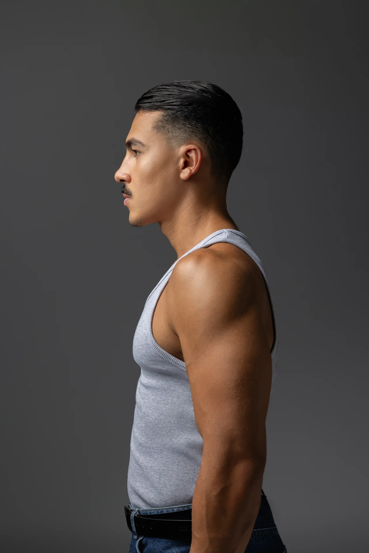 Side profile in a grey ribbed tank top showing shoulders and arms. Male modeling portfolio photoshoot by MRPS in Dubai, photographed by Nastaran.