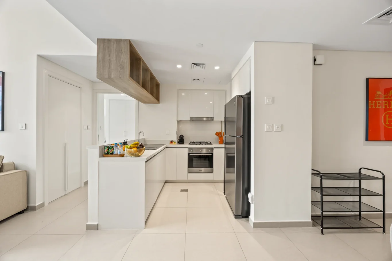 White kitchen with full height cabinets, fridge and breakfast counter. Day, twilight and night Airbnb photography by MRPS for Vista Haus Holiday Homes in Downtown Dubai.